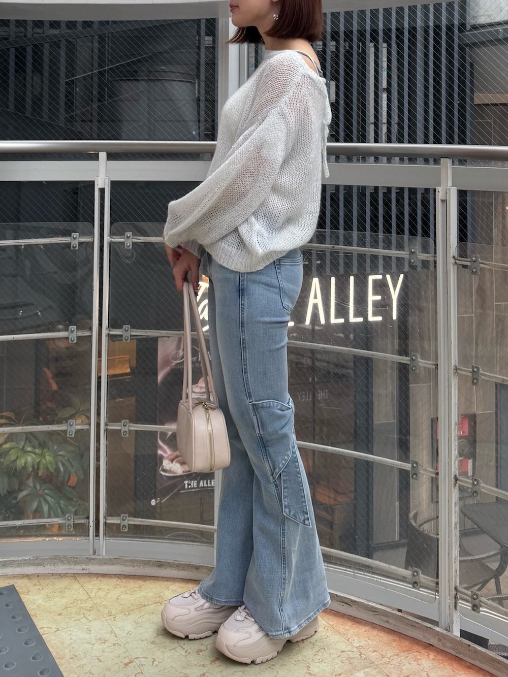 ブルー系のデニムパンツ、ホワイト系のニット/セーター、ホワイト系のハンドバッグを着用したレディースの春コーディネートの3枚目の写真