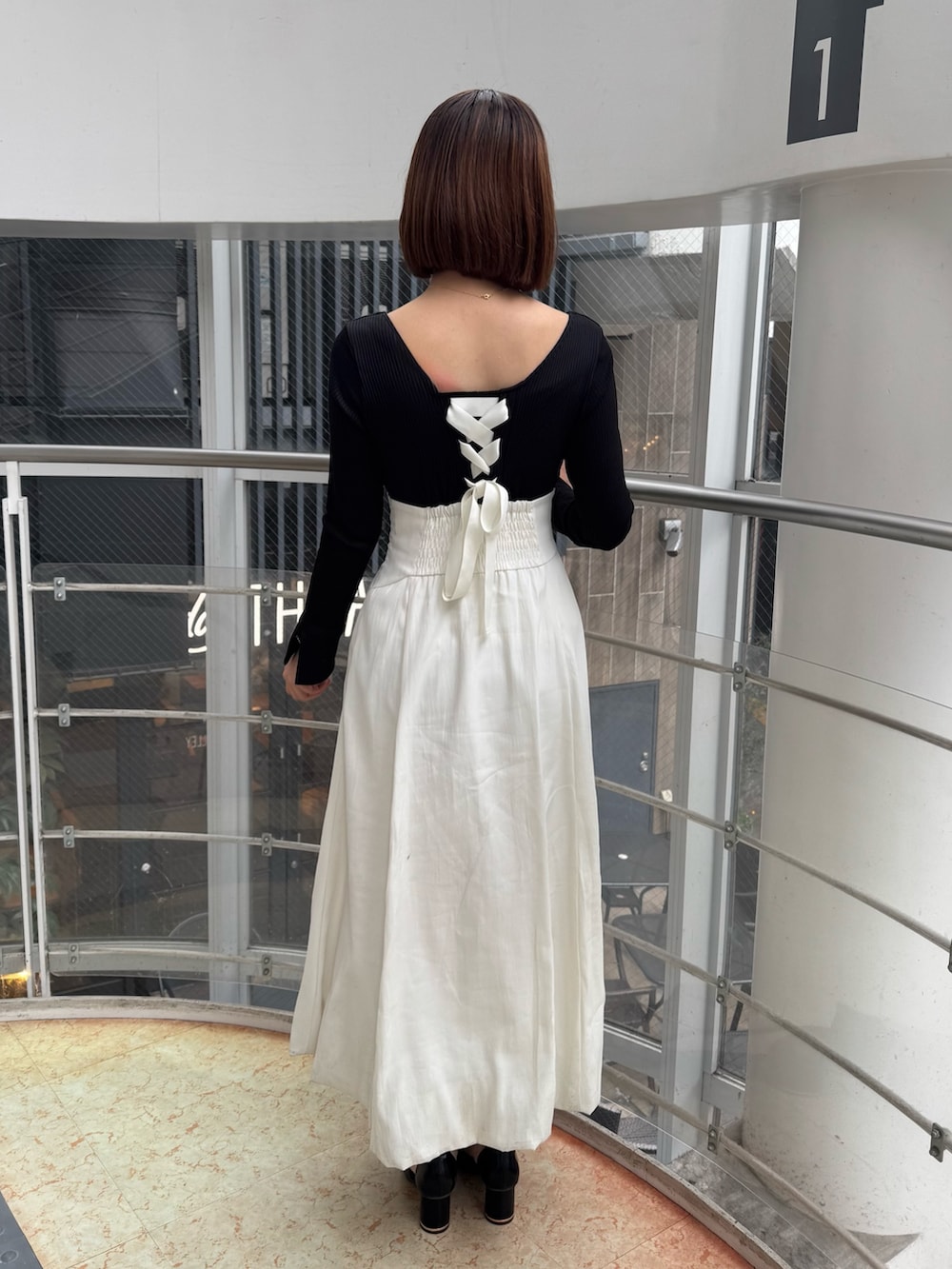 ホワイト系のワンピース、ブラック系のサンダルを着用したレディースの冬コーディネートの4枚目の写真