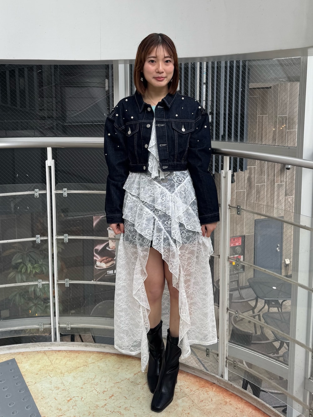 ブルー系のデニムジャケット、ホワイト系のキャミソール、ブルー系のデニムパンツを着用したレディースの冬コーディネートの2枚目の写真