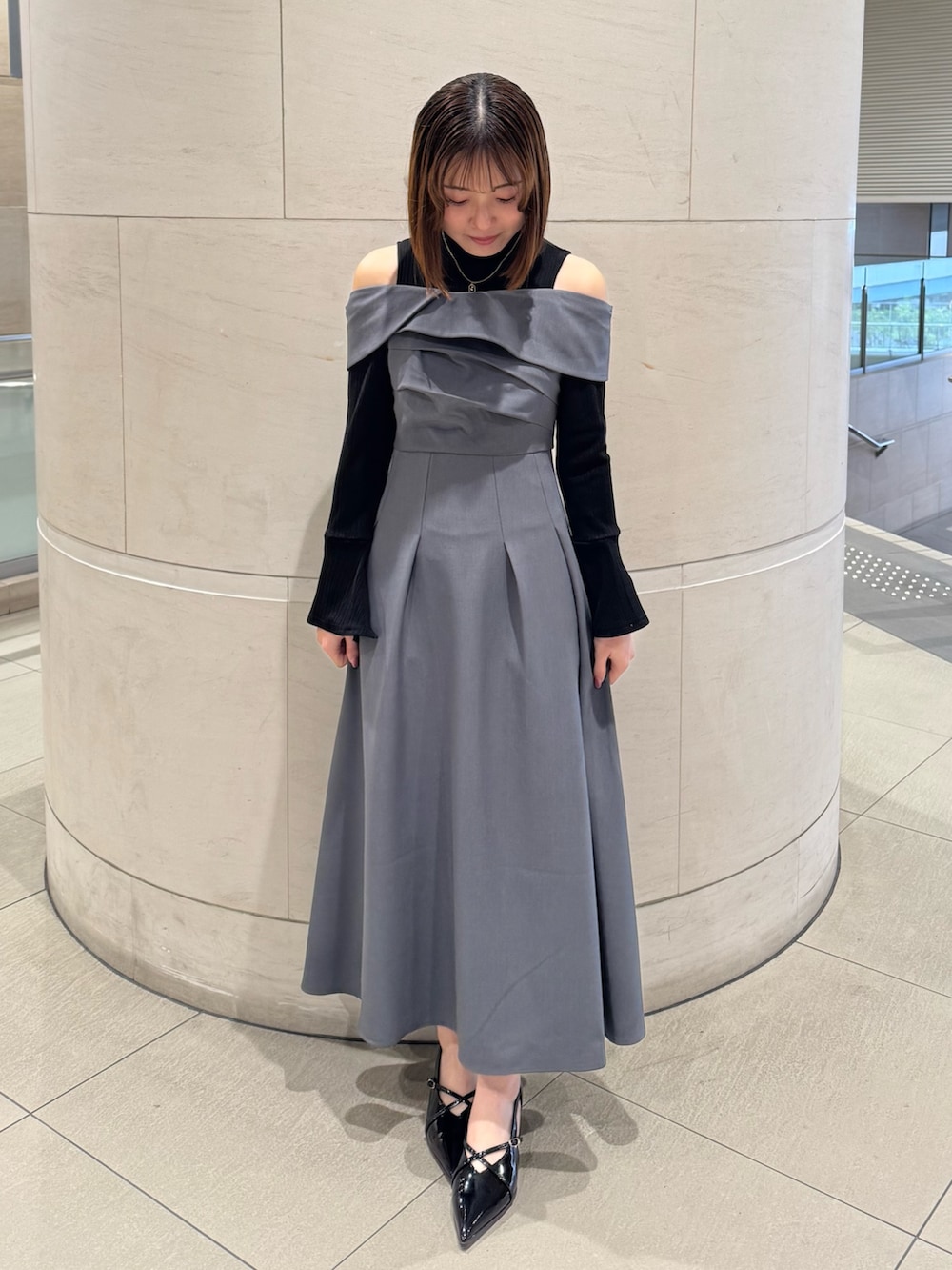 グレー系のワンピース、ブラック系のパンプスを着用したレディースの冬コーディネートの2枚目の写真