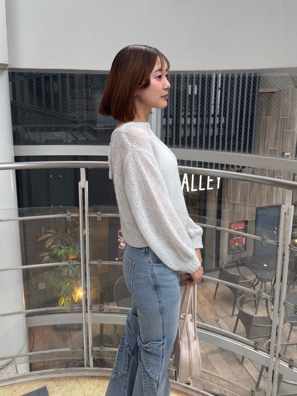 ブルー系のデニムパンツ、ホワイト系のニット/セーター、ホワイト系のハンドバッグを着用したレディースの春コーディネートの7枚目の写真