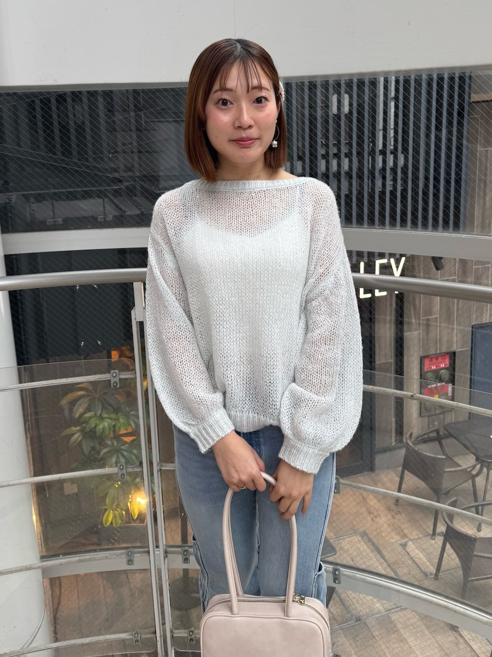 ブルー系のデニムパンツ、ホワイト系のニット/セーター、ホワイト系のハンドバッグを着用したレディースの春コーディネートの6枚目の写真