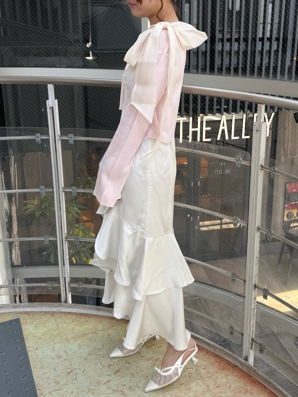 ホワイト系のワンピース、ピンク系のカーディガン/ボレロ、ホワイト系のパンプスを着用したレディースの春コーディネートの2枚目の写真