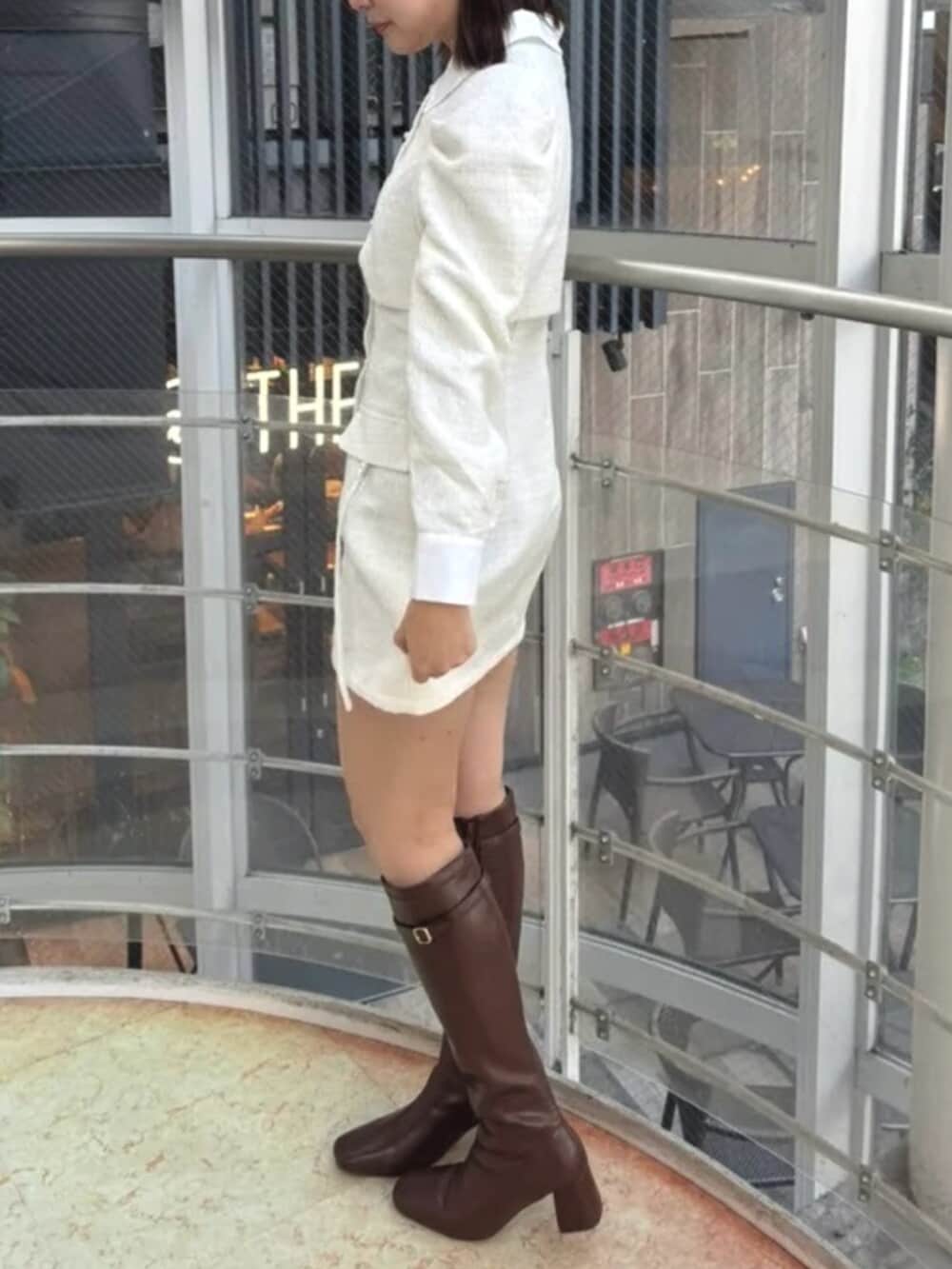 ホワイト系のワンピース、ブラウン系のブーツを着用したレディースの冬コーディネートの2枚目の写真