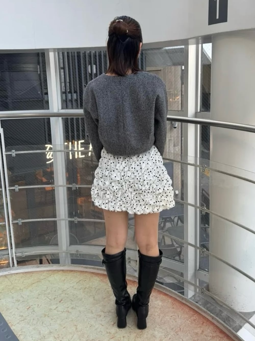 ホワイト系のスカート、グレー系のブルゾン、ブラック系のブーツを着用したレディースの冬コーディネートの3枚目の写真