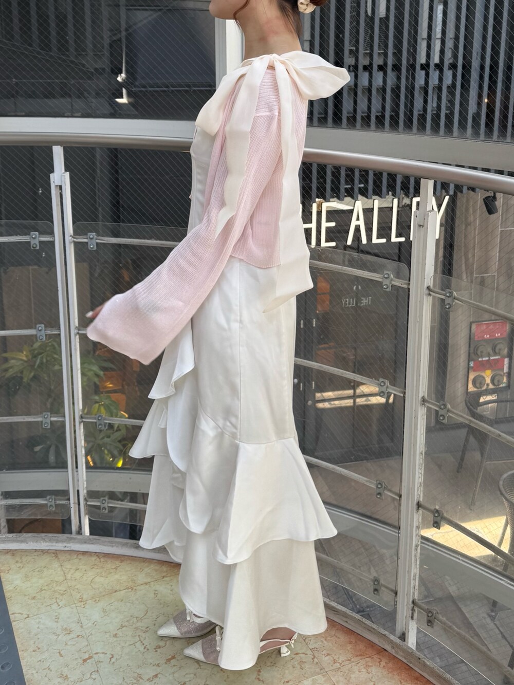 ホワイト系のワンピース、ピンク系のカーディガン/ボレロ、ホワイト系のパンプスを着用したレディースの春コーディネートの3枚目の写真