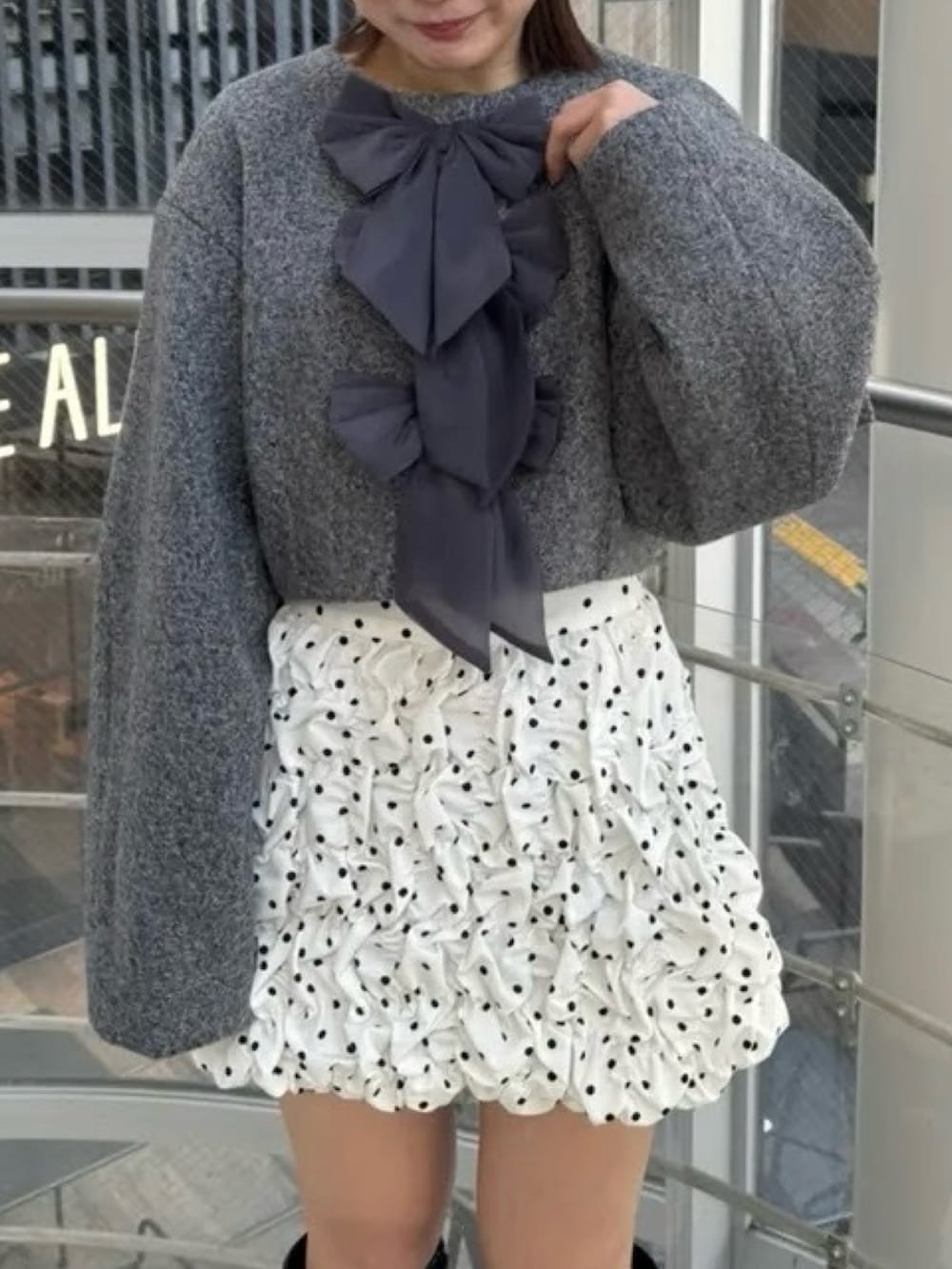 ホワイト系のスカート、グレー系のブルゾン、ブラック系のブーツを着用したレディースの冬コーディネートの6枚目の写真