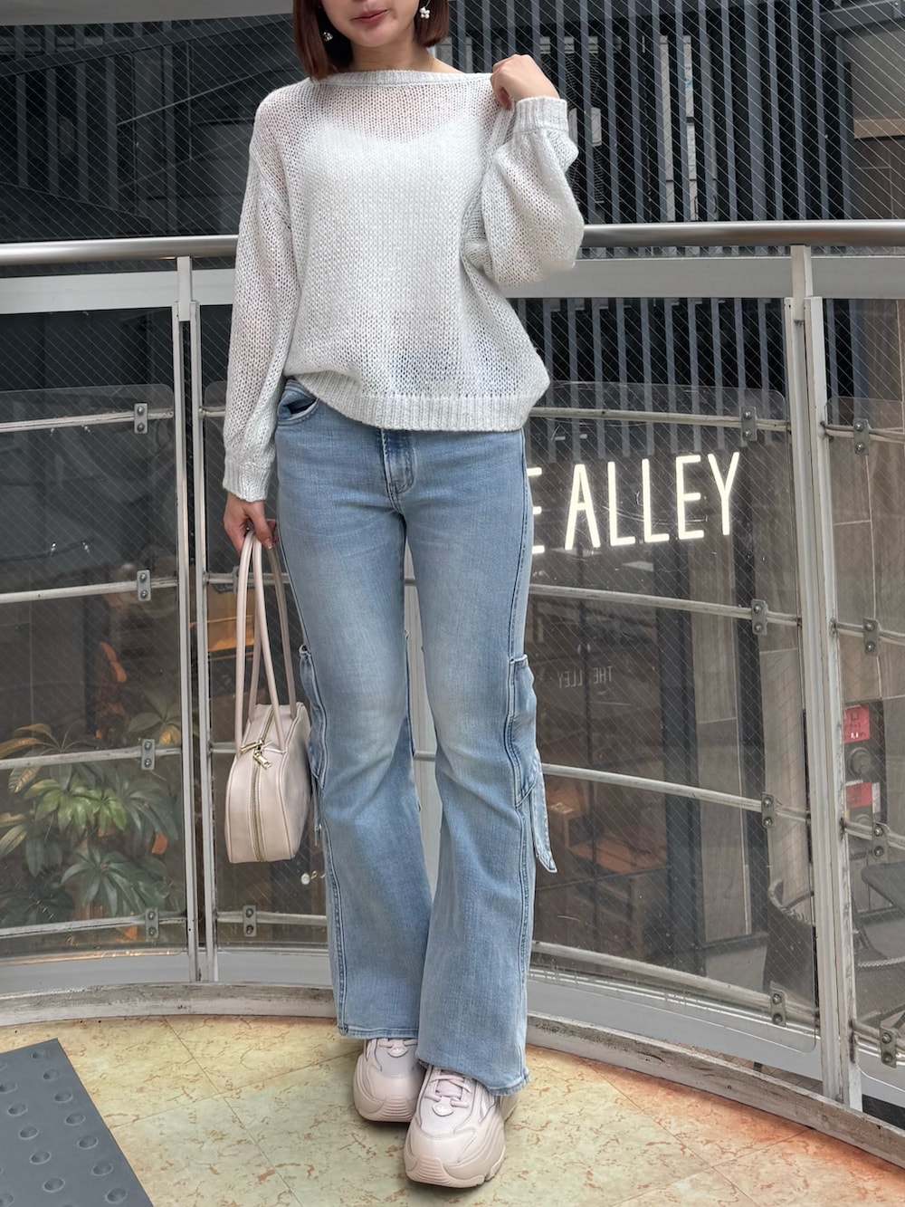 ブルー系のデニムパンツ、ホワイト系のニット/セーター、ホワイト系のハンドバッグを着用したレディースの春コーディネートの2枚目の写真