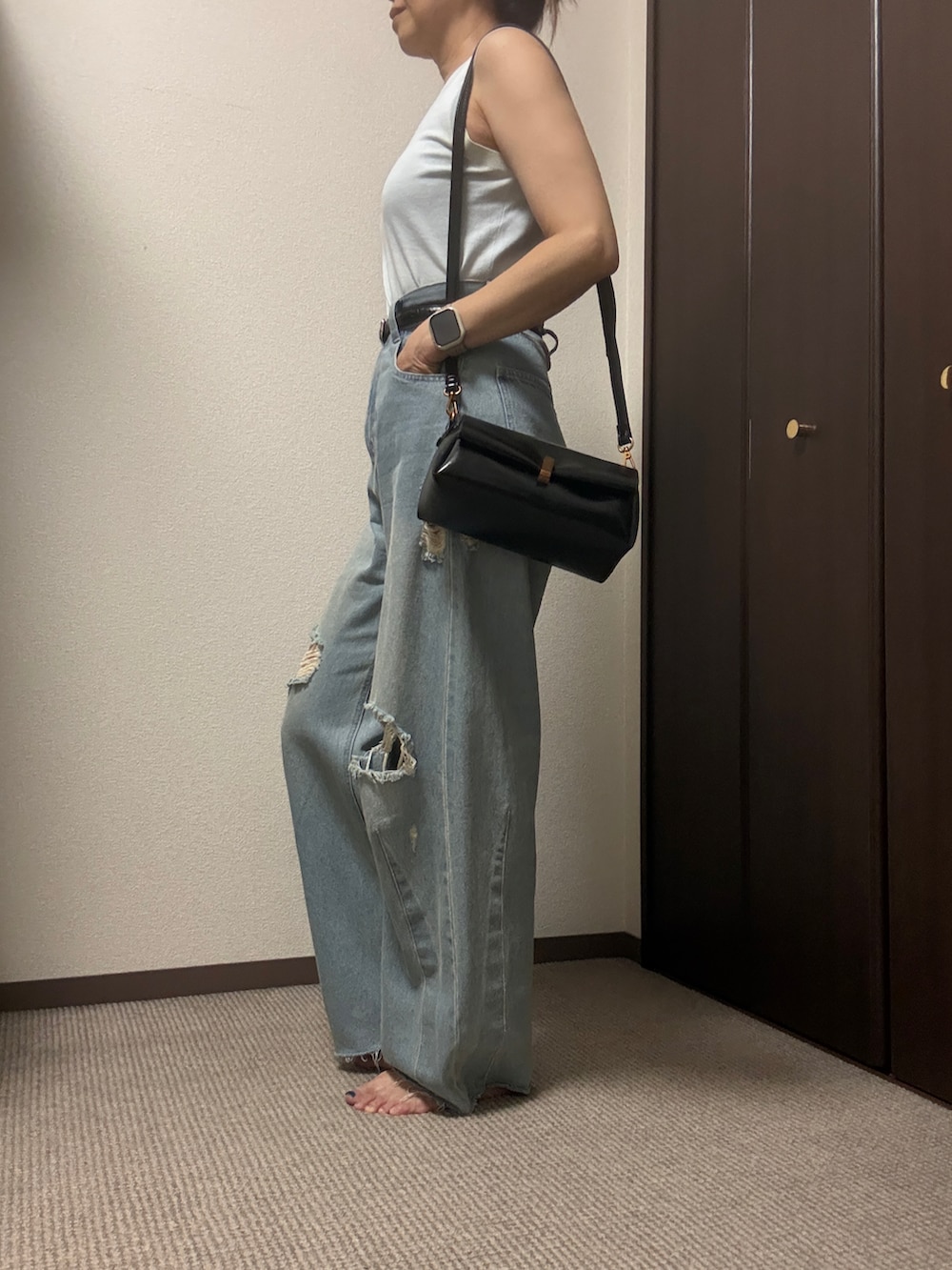 ブルー系のデニムパンツ、ブラック系のショルダーバッグ、ブラウン系のベルトを着用したレディースの夏コーディネートの2枚目の写真