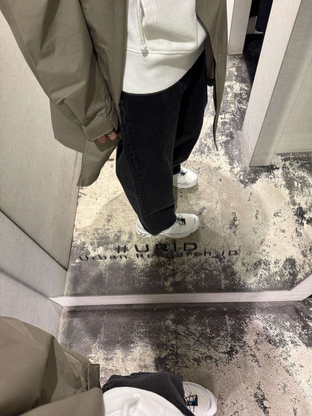 ホワイト系のパーカー、グレー系のステンカラーコート、ブラック系のデニムパンツを着用したメンズの冬コーディネートの4枚目の写真