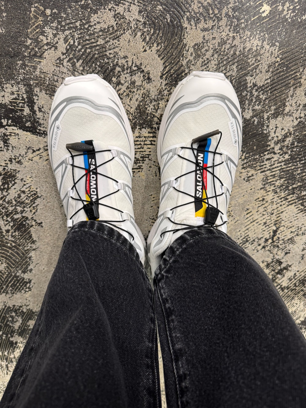 ホワイト系のパーカー、グレー系のステンカラーコート、ブラック系のデニムパンツを着用したメンズの冬コーディネートの5枚目の写真