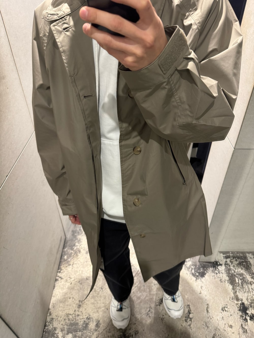 ホワイト系のパーカー、グレー系のステンカラーコート、ブラック系のデニムパンツを着用したメンズの冬コーディネートの3枚目の写真