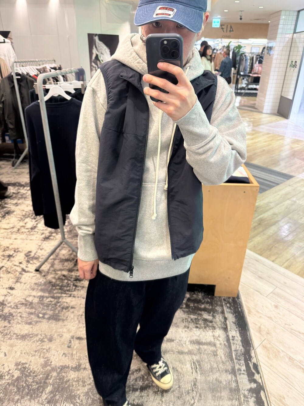 グレー系のパーカー、ブルー系のベスト、ブルー系のデニムパンツを着用したメンズの冬コーディネートの2枚目の写真