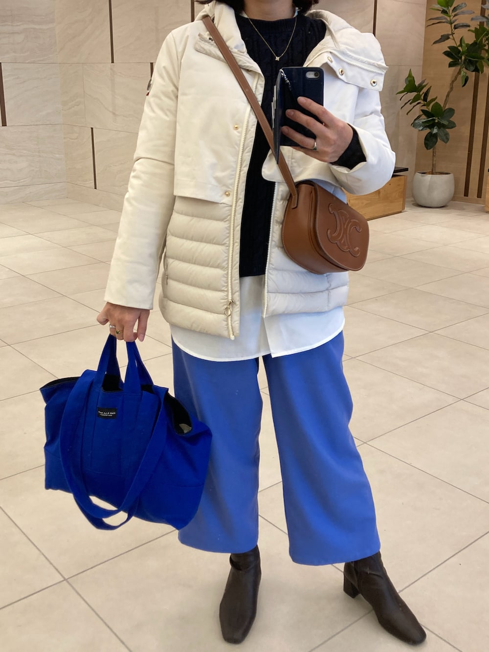 ブルー系のパンツ、ブラウン系のブーツ、ブルー系のトートバッグを着用したレディースの春コーディネートの2枚目の写真