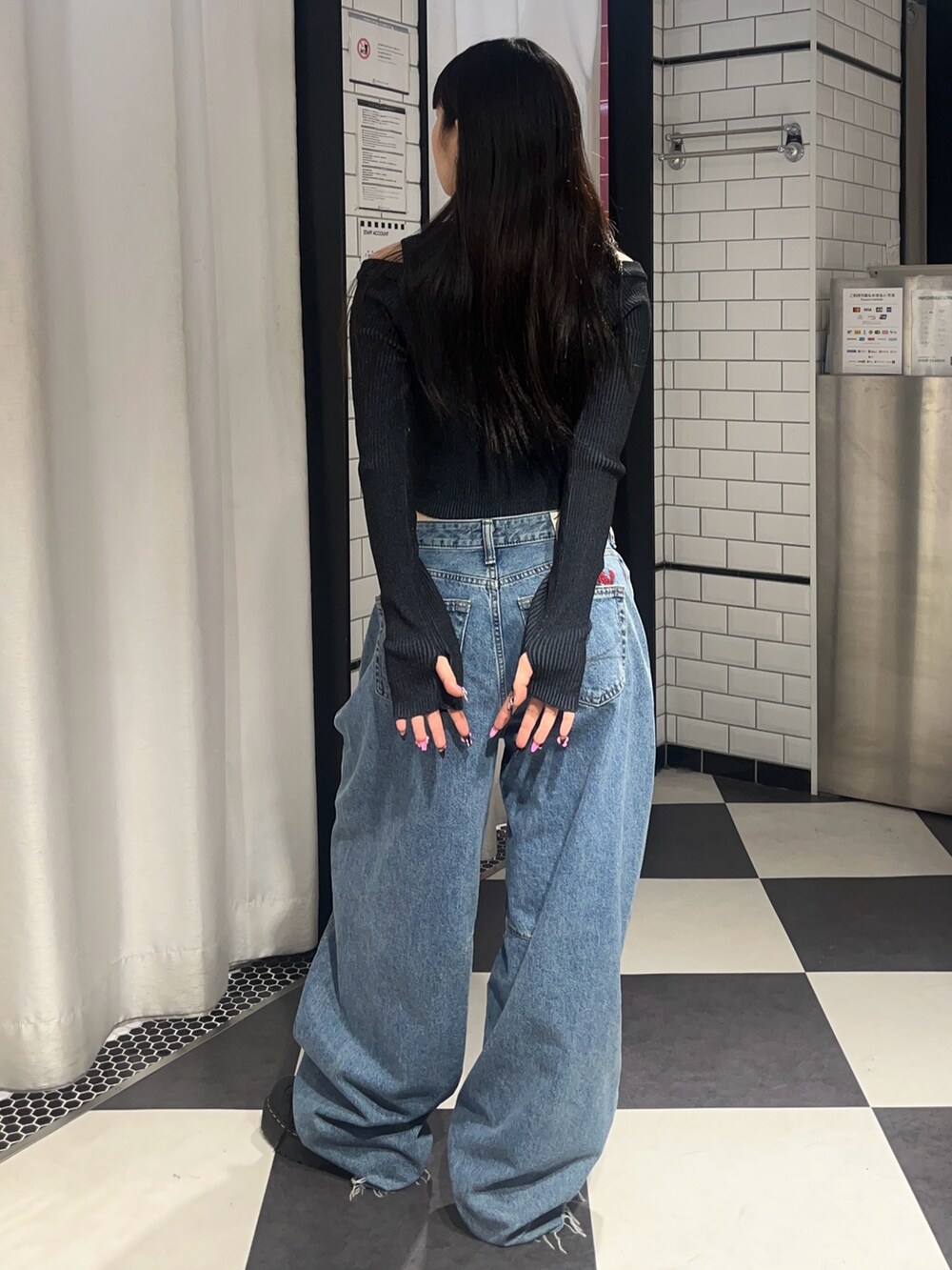 ブルー系のデニムパンツ、ブラック系のニット/セーター、ブラック系のブーツを着用したレディースの春コーディネートの3枚目の写真