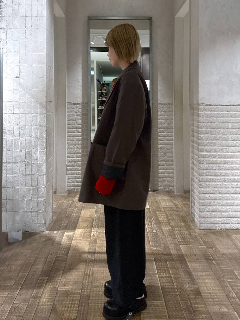 グレー系のテーラードジャケット、ブラック系のスラックス、レッド系のカーディガン/ボレロを着用したレディースの秋コーディネートの2枚目の写真