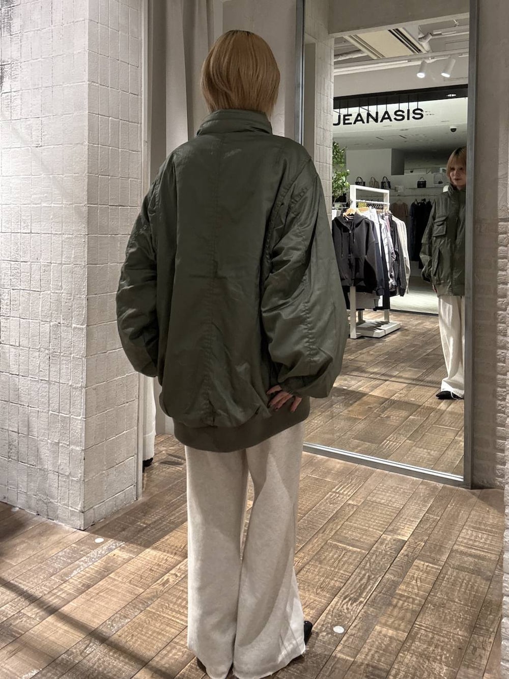 グリーン系のブルゾン、ブラック系のパンプス、ホワイト系のデニムパンツを着用したレディースの冬コーディネートの4枚目の写真