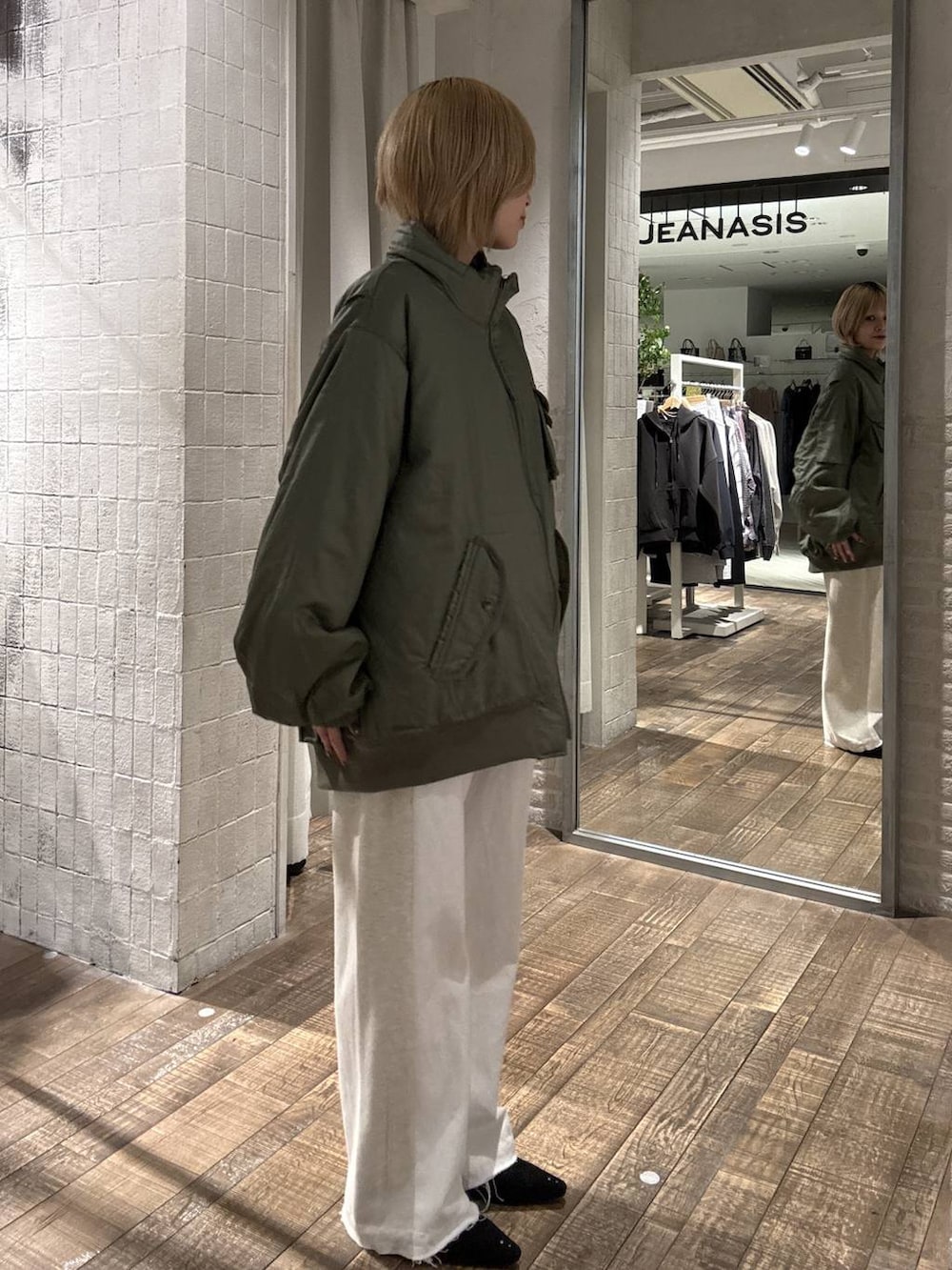 グリーン系のブルゾン、ブラック系のパンプス、ホワイト系のデニムパンツを着用したレディースの冬コーディネートの3枚目の写真