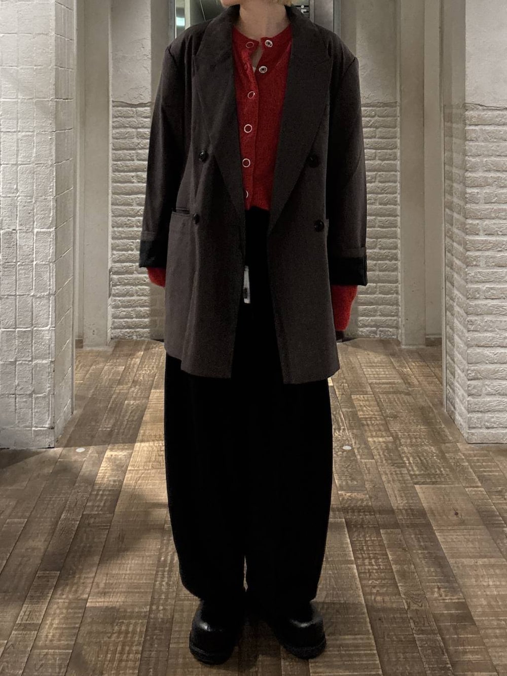 グレー系のテーラードジャケット、ブラック系のスラックス、レッド系のカーディガン/ボレロを着用したレディースの秋コーディネートの4枚目の写真