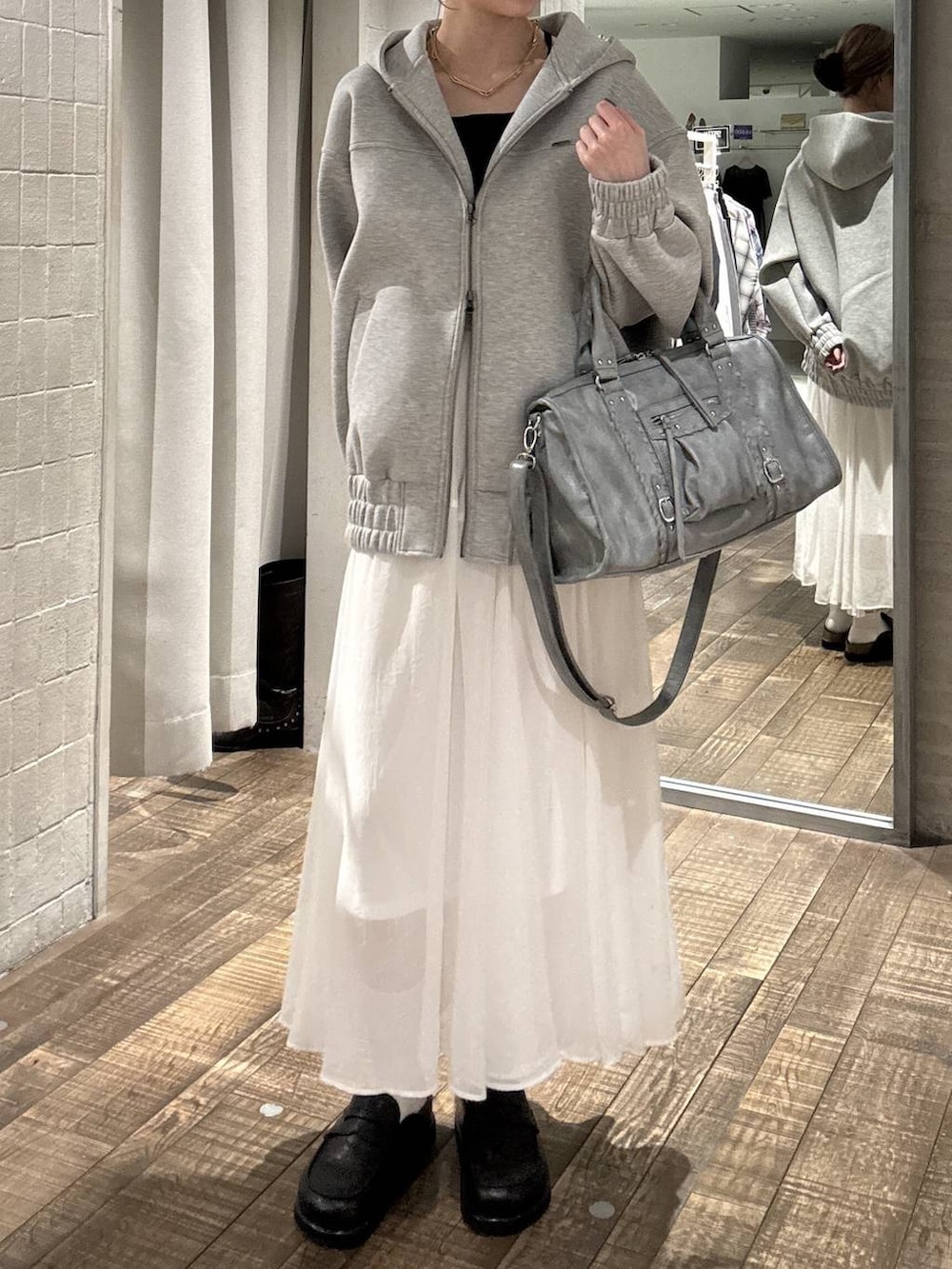 グレー系のブルゾン、ブラック系のローファー、ブルー系のボストンバッグを着用したレディースの春コーディネートの4枚目の写真