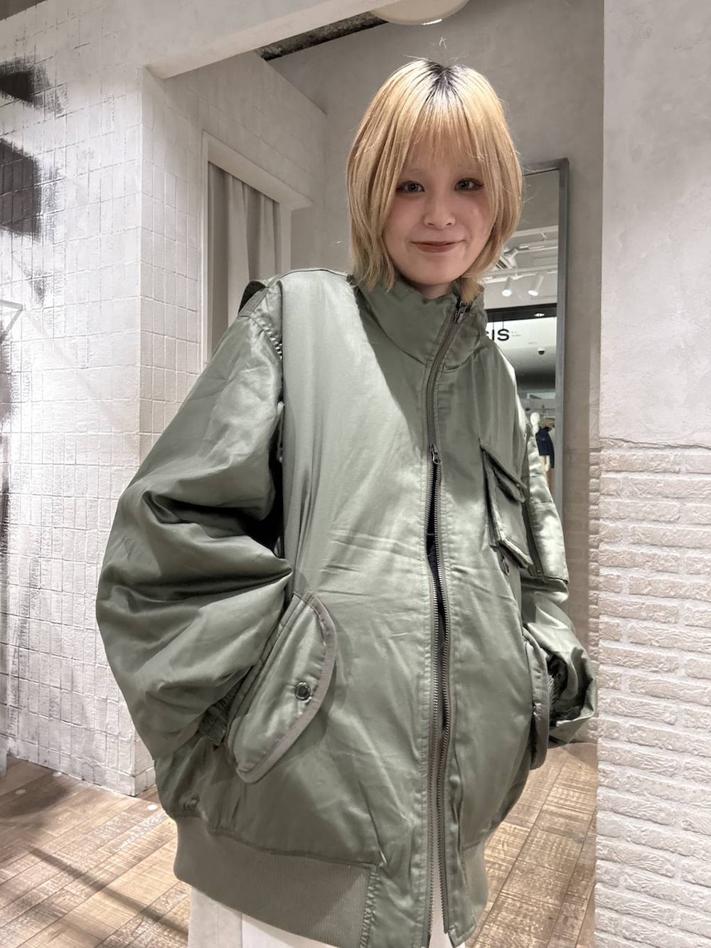 グリーン系のブルゾン、ブラック系のパンプス、ホワイト系のデニムパンツを着用したレディースの冬コーディネートの2枚目の写真