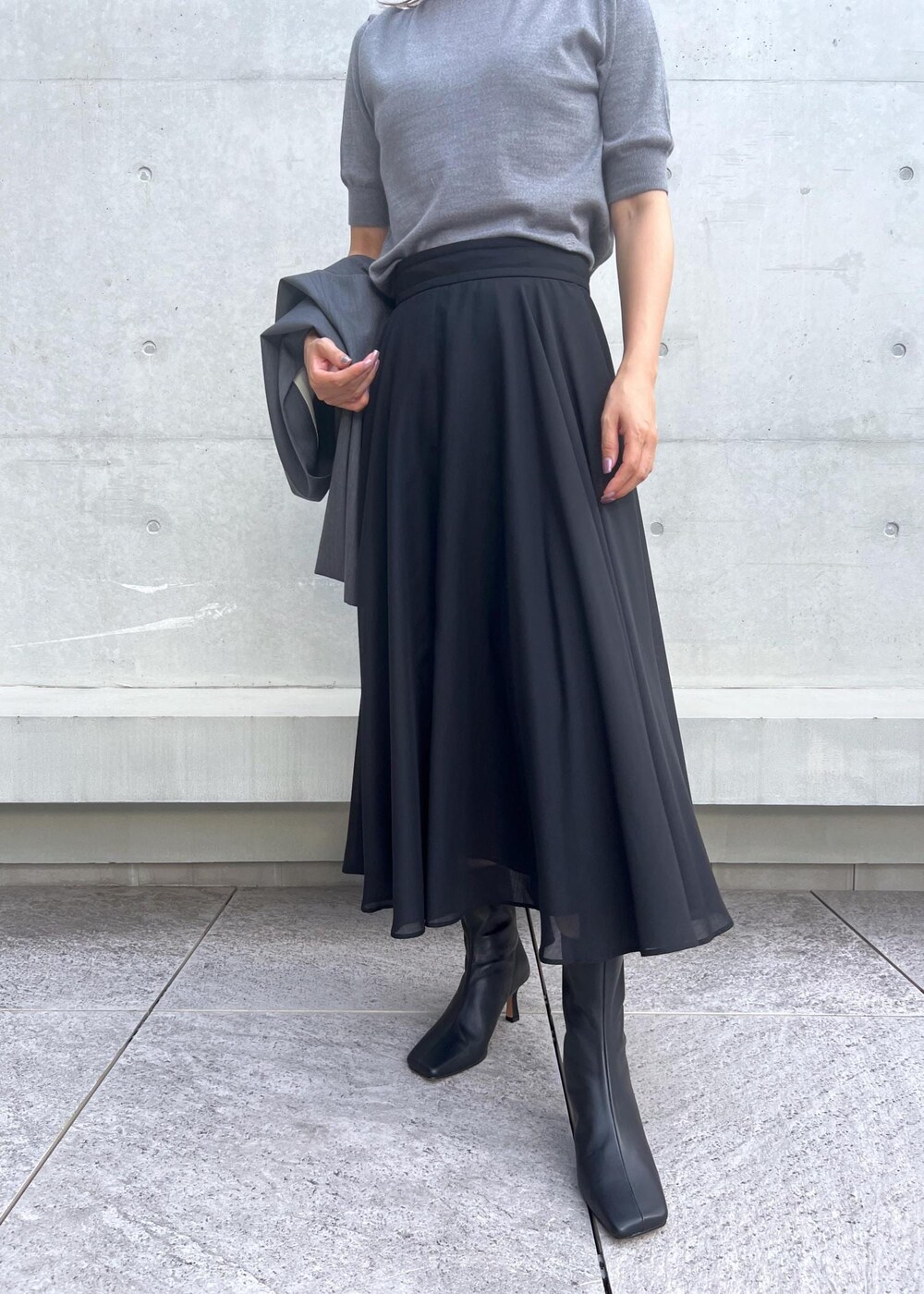 ブラック系のブーツ、ブラック系のスカート、グレー系のベストを着用したレディースの秋コーディネートの5枚目の写真