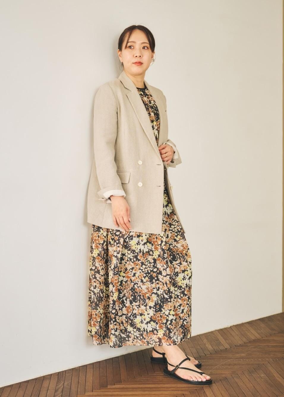 ベージュ系のテーラードジャケット、ブラック系のサンダル、ブラウン系のワンピースを着用したレディースの春コーディネートの3枚目の写真