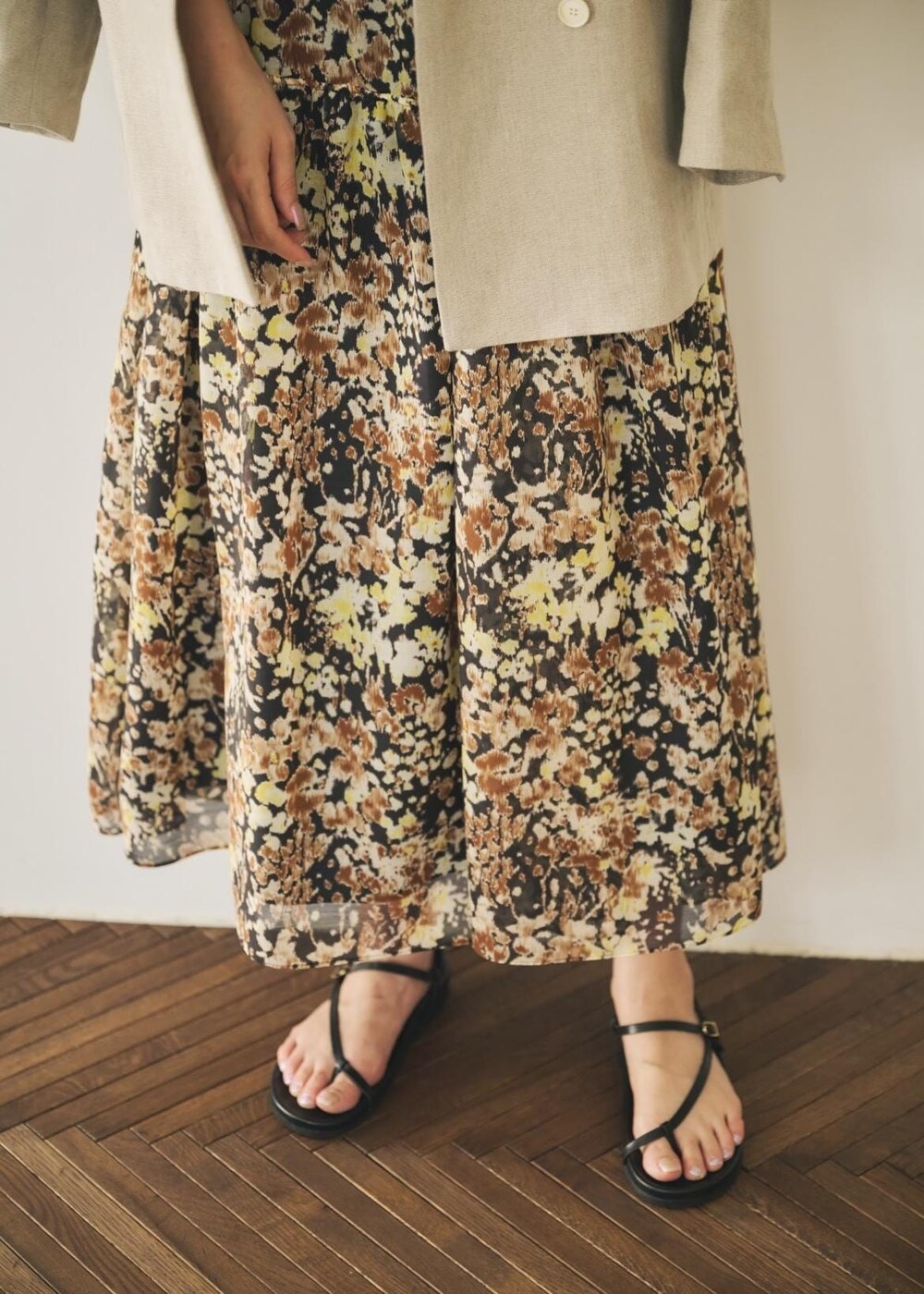 ベージュ系のテーラードジャケット、ブラック系のサンダル、ブラウン系のワンピースを着用したレディースの春コーディネートの5枚目の写真