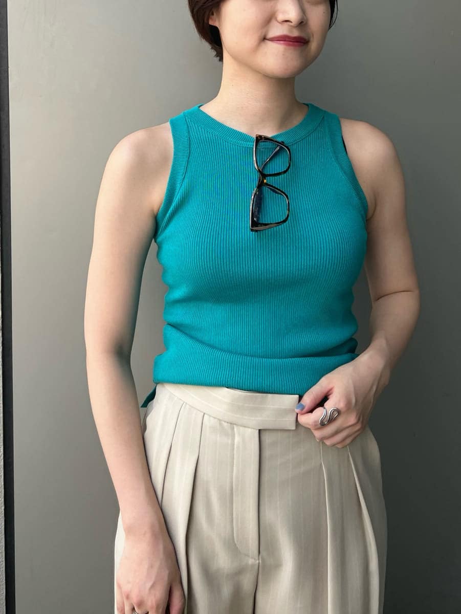 ブルー系のニット/セーター、ベージュ系のその他パンツ、ブラウン系のショルダーバッグを着用したレディースの夏コーディネートの5枚目の写真