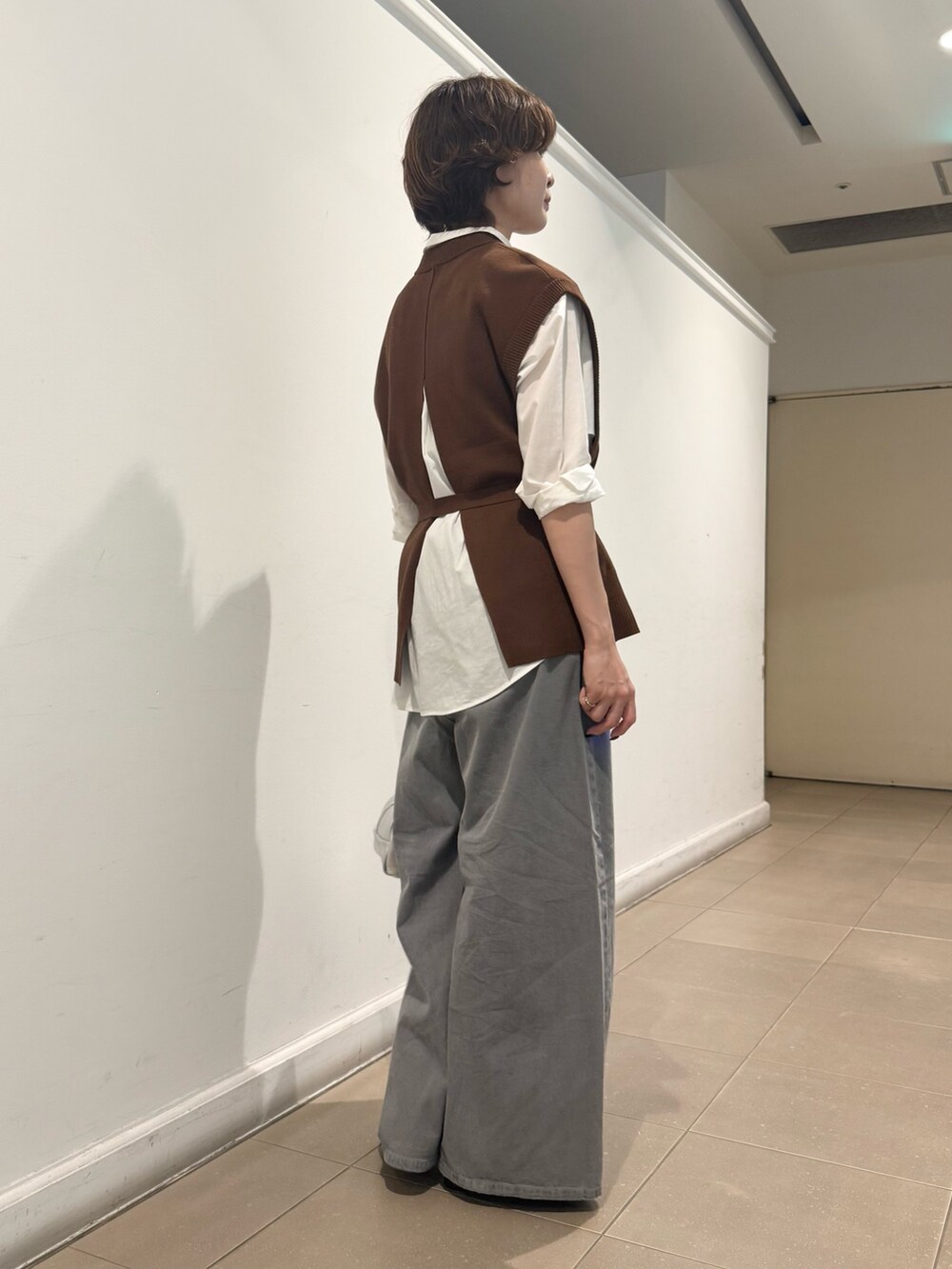 ブラウン系のベスト、ホワイト系のシャツ/ブラウス、グレー系のデニムパンツを着用したレディースの秋コーディネートの3枚目の写真