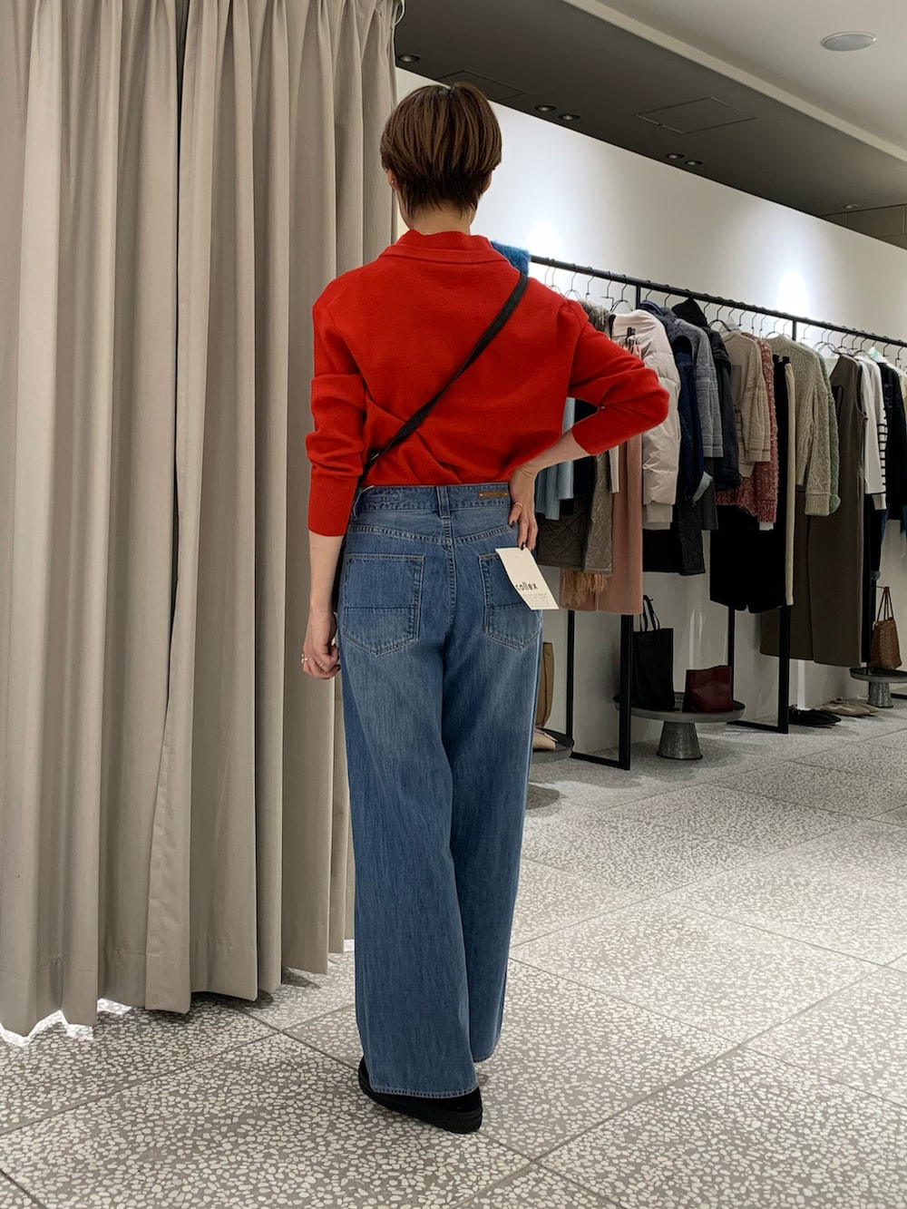 レッド系のニット/セーター、ブラック系のショルダーバッグ、ブルー系のデニムパンツを着用したレディースの冬コーディネートの3枚目の写真