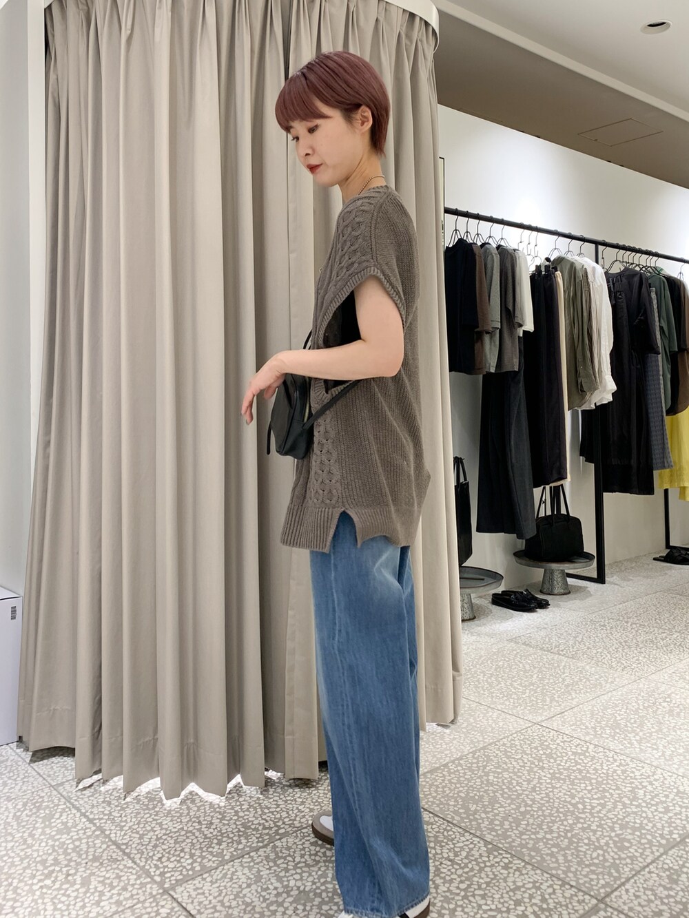 ブラック系のショルダーバッグ、ブルー系のデニムパンツ、ベージュ系のニット/セーターを着用したレディースの夏コーディネートの3枚目の写真