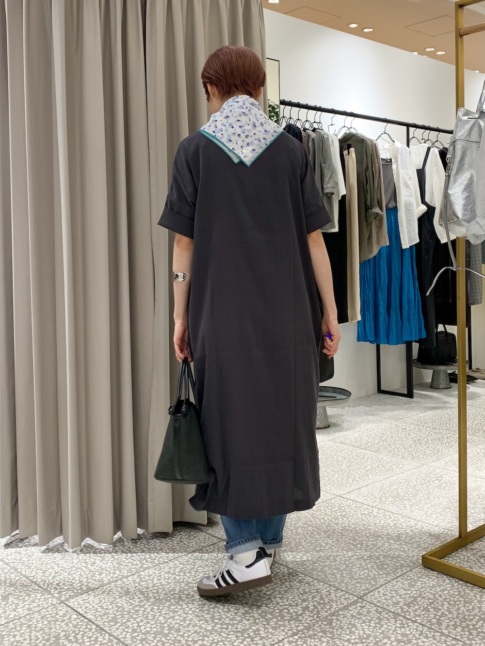 グレー系のワンピース、ブラック系のかごバッグ、ブルー系のデニムパンツを着用したレディースの夏コーディネートの2枚目の写真