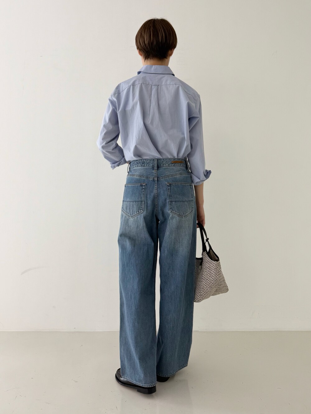 ブルー系のシャツ/ブラウス、ブルー系のデニムパンツ、ブラック系のかごバッグを着用したレディースの春コーディネートの3枚目の写真