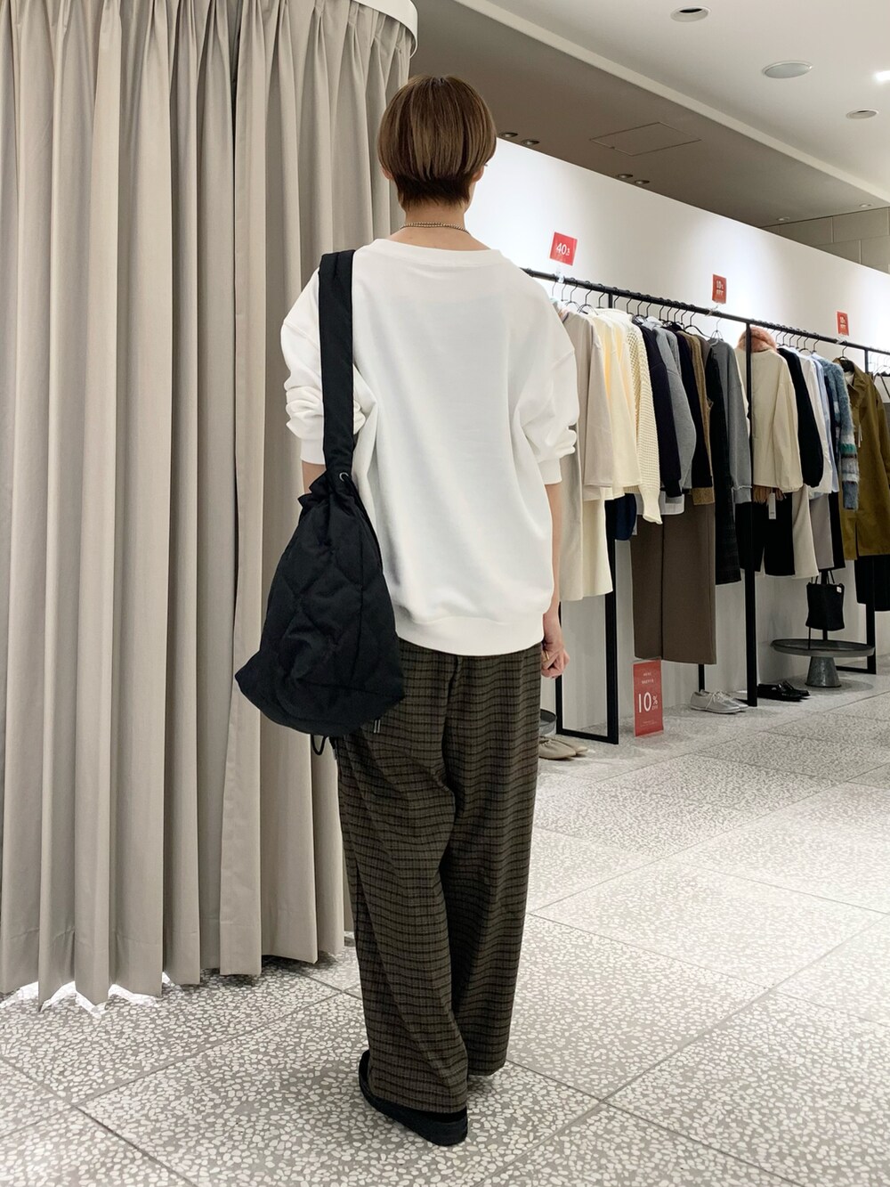 ホワイト系のスウェット、ブラック系のショルダーバッグ、ブラウン系のその他パンツを着用したレディースの冬コーディネートの3枚目の写真