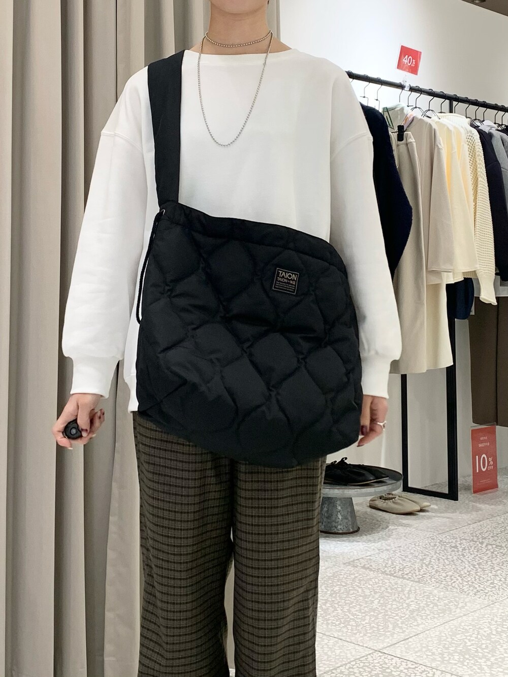 ホワイト系のスウェット、ブラック系のショルダーバッグ、ブラウン系のその他パンツを着用したレディースの冬コーディネートの4枚目の写真