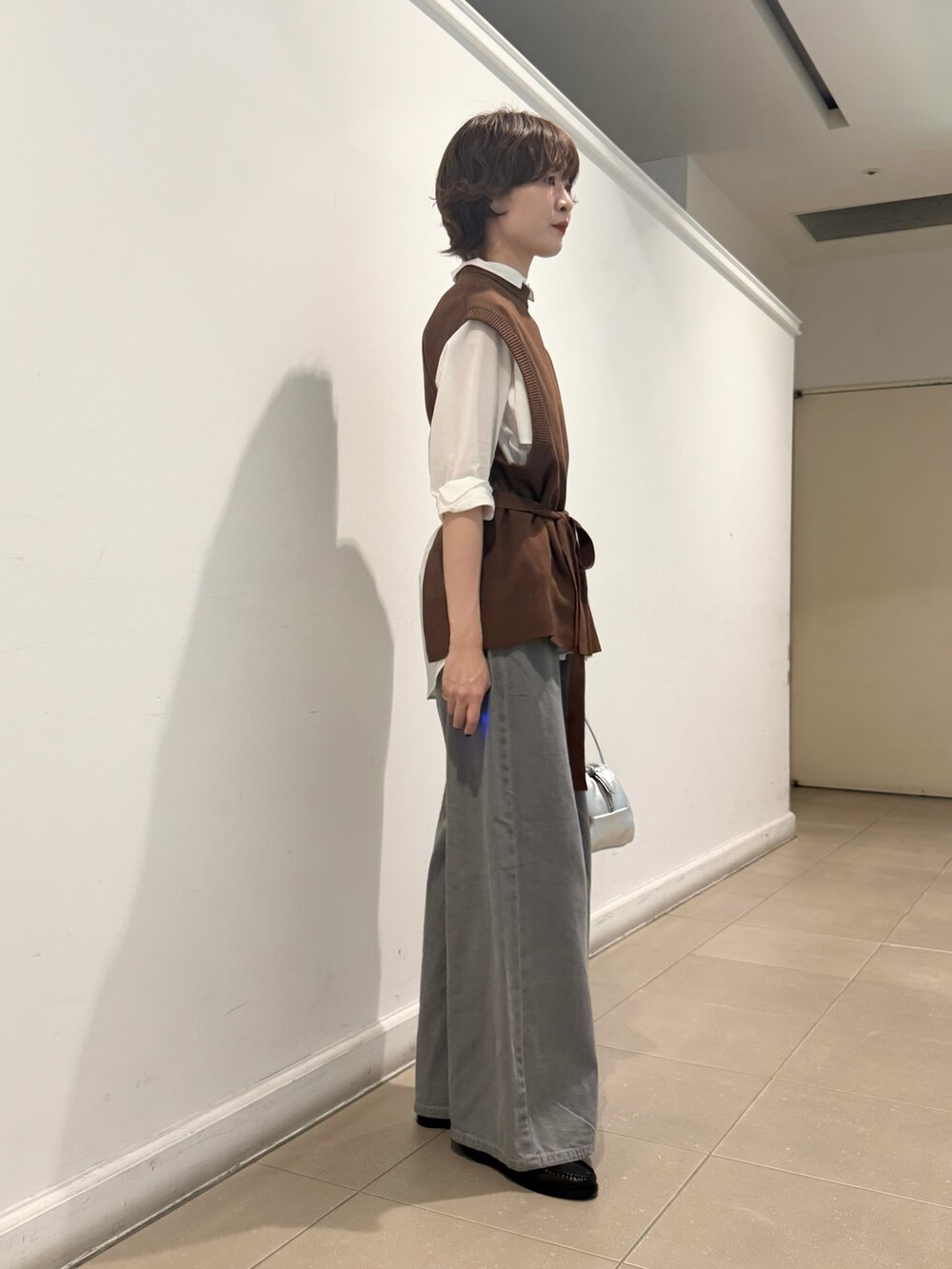 ブラウン系のベスト、ホワイト系のシャツ/ブラウス、グレー系のデニムパンツを着用したレディースの秋コーディネートの2枚目の写真