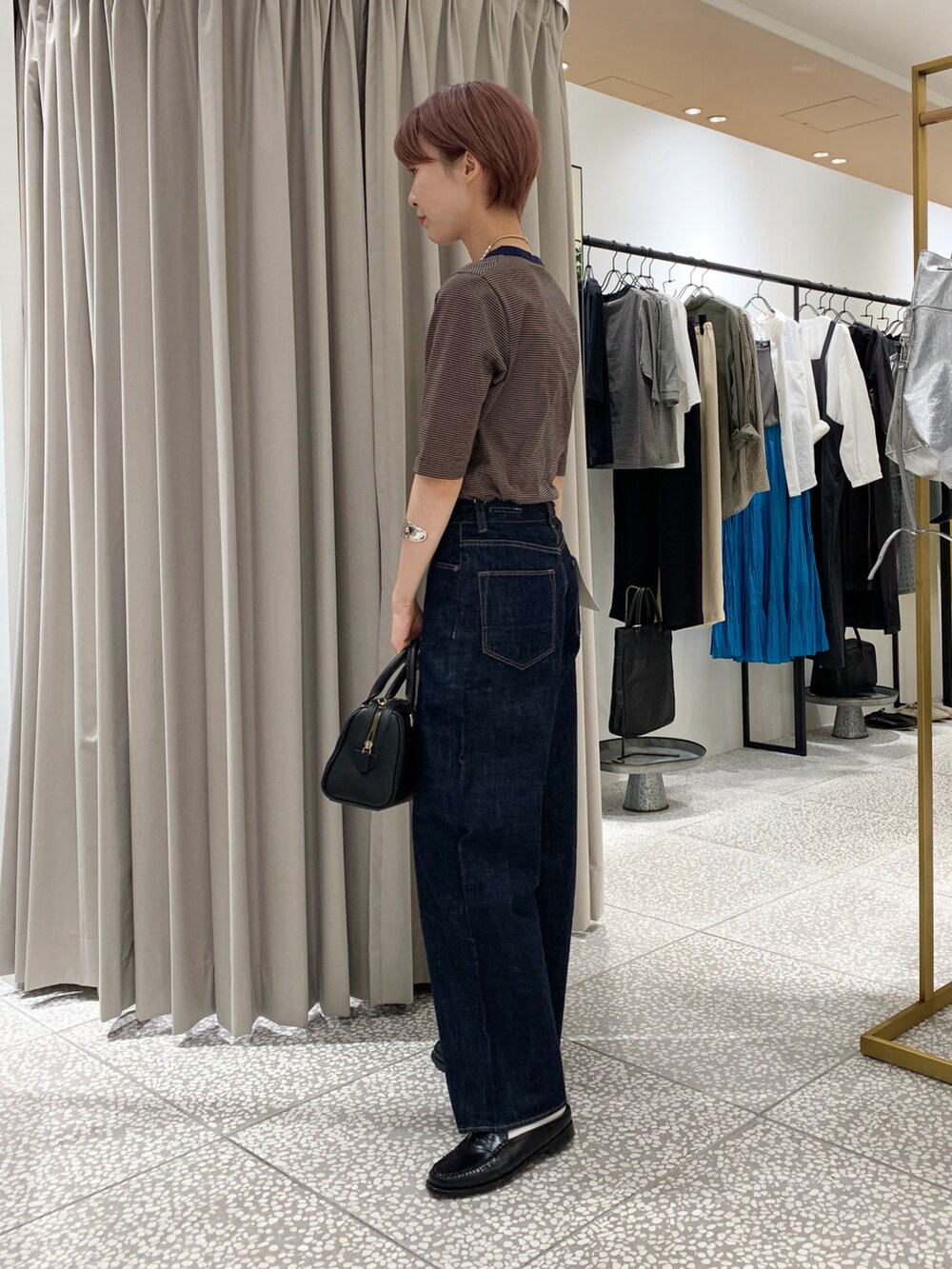 ベージュ系のTシャツ/カットソー、ブルー系のデニムパンツ、ブラック系のボストンバッグを着用したレディースの夏コーディネートの2枚目の写真