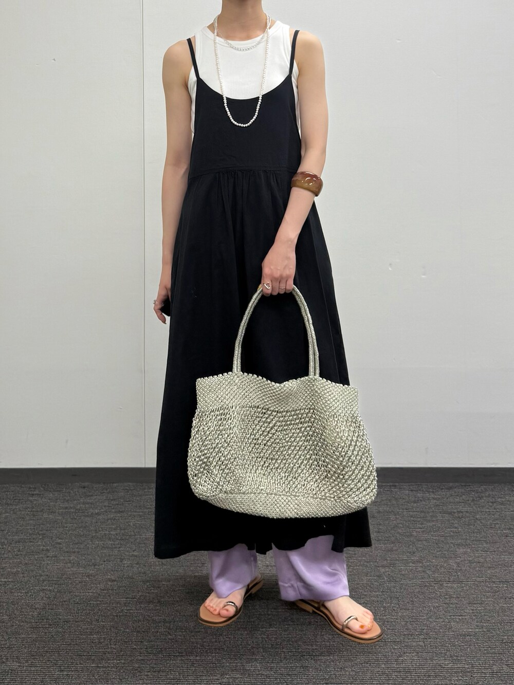 ブラック系のワンピース、ゴールド系のかごバッグ、グリーン系のその他パンツを着用したレディースの夏コーディネートの4枚目の写真