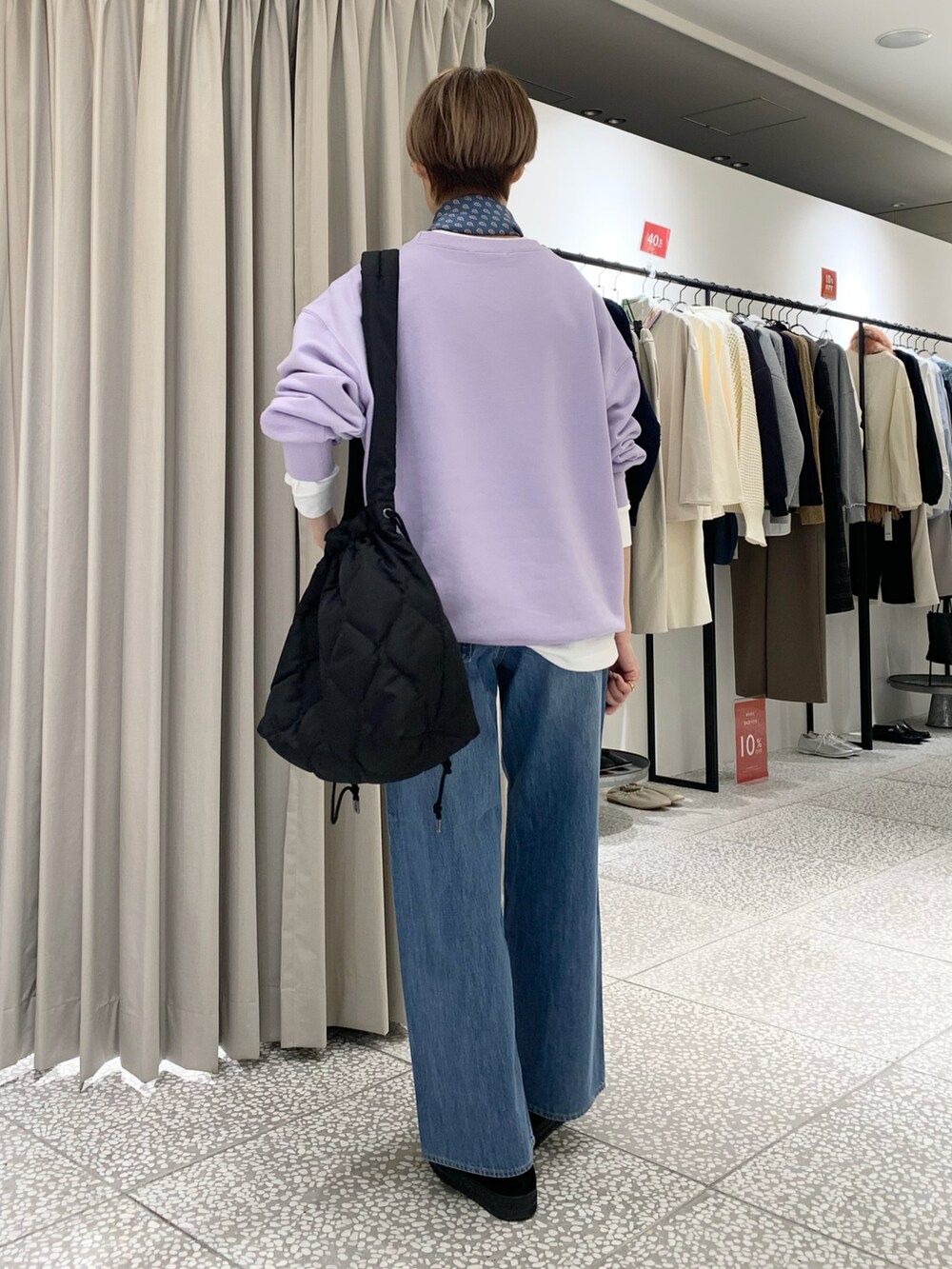 パープル系のスウェット、ブラック系のショルダーバッグ、ブルー系のデニムパンツを着用したレディースの冬コーディネートの3枚目の写真