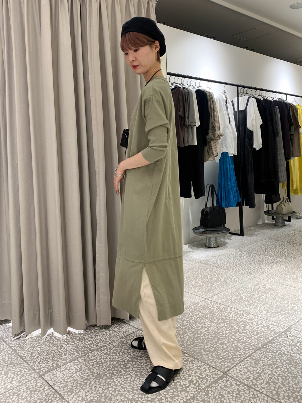 グリーン系のワンピース、ホワイト系のその他パンツ、ブラック系のサンダルを着用したレディースの秋コーディネートの2枚目の写真