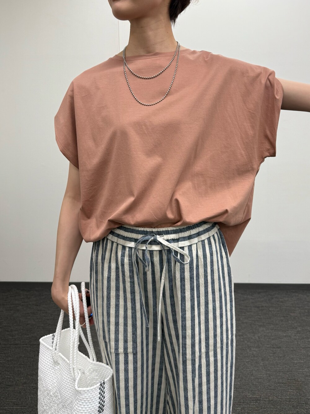 ピンク系のTシャツ/カットソー、ブラック系のその他パンツ、ブラック系のサンダルを着用したレディースの夏コーディネートの5枚目の写真