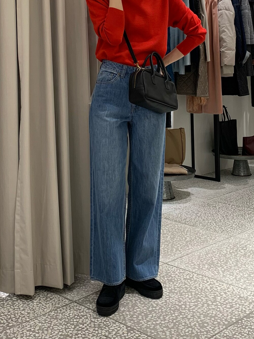 レッド系のニット/セーター、ブラック系のショルダーバッグ、ブルー系のデニムパンツを着用したレディースの冬コーディネートの5枚目の写真