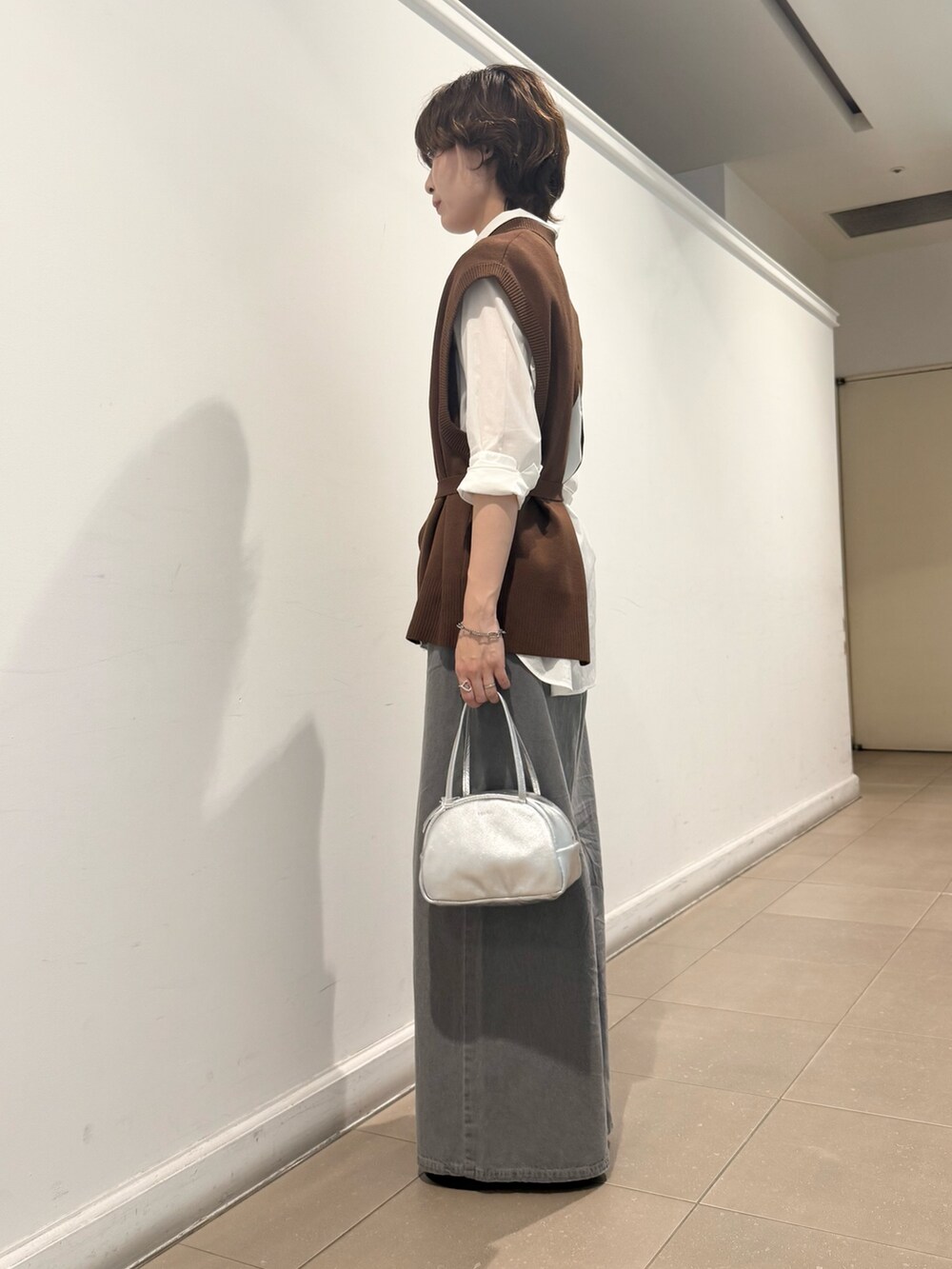 ブラウン系のベスト、ホワイト系のシャツ/ブラウス、グレー系のデニムパンツを着用したレディースの秋コーディネートの4枚目の写真