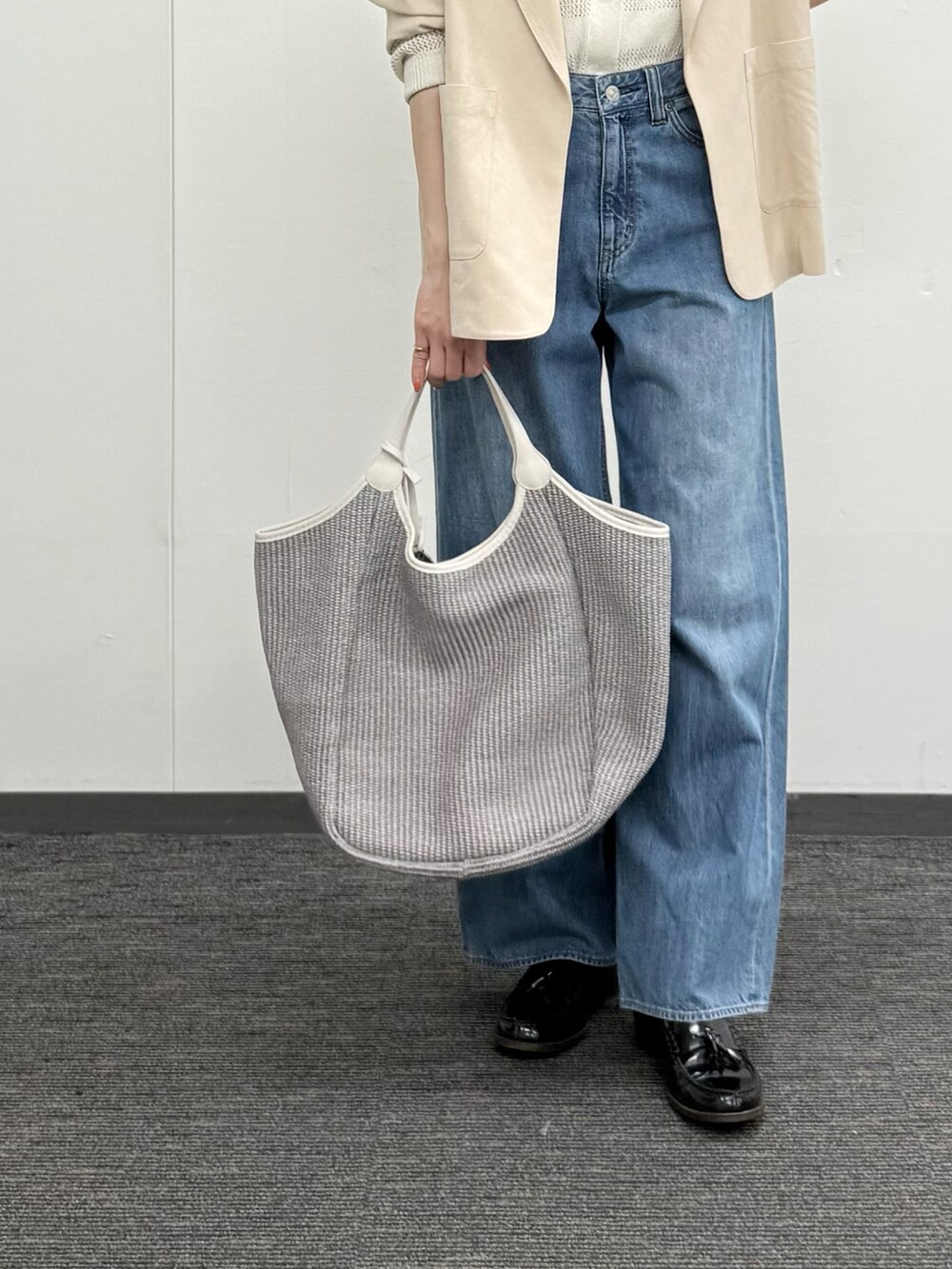 ホワイト系のカーディガン/ボレロ、ベージュ系のテーラードジャケット、ブルー系のデニムパンツを着用したレディースの春コーディネートの4枚目の写真