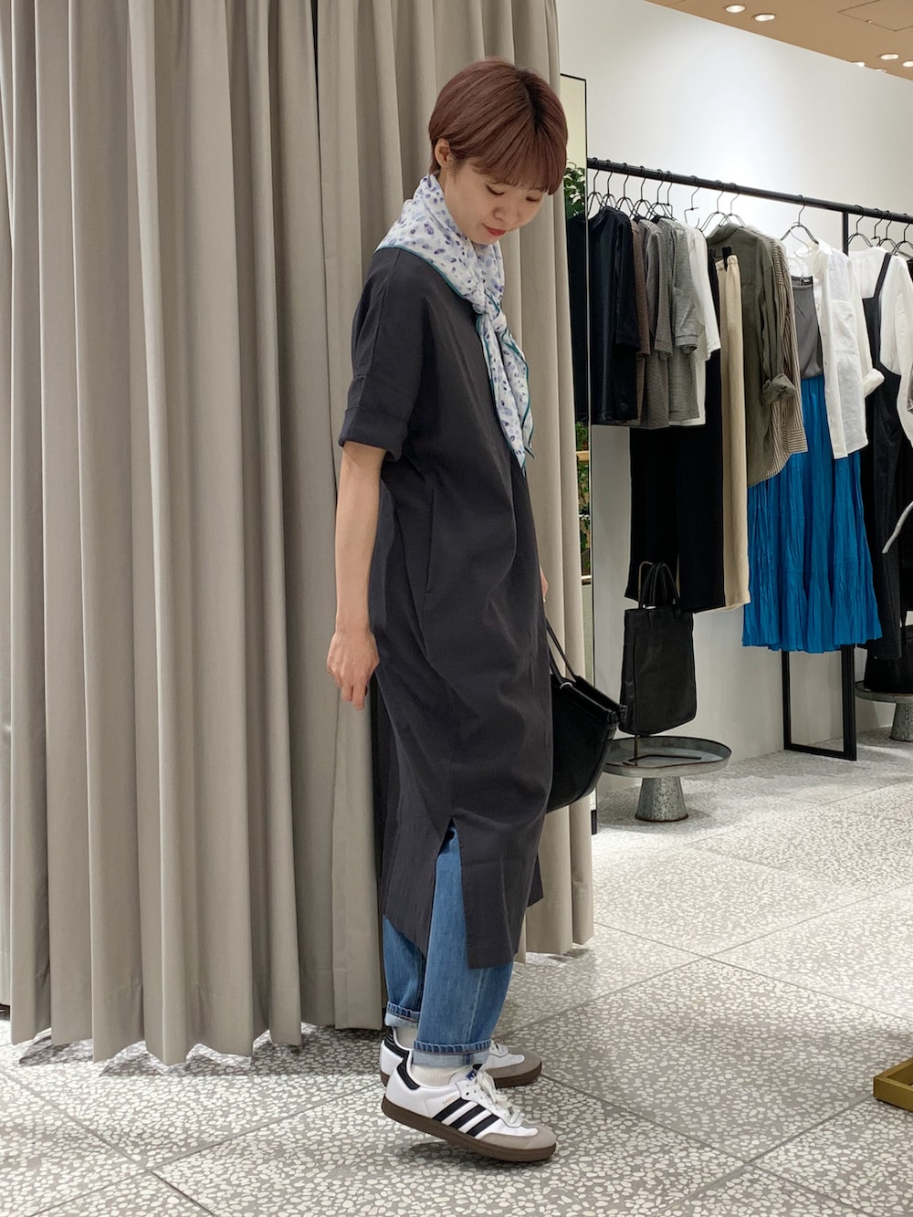 グレー系のワンピース、ブラック系のかごバッグ、ブルー系のデニムパンツを着用したレディースの夏コーディネートの3枚目の写真