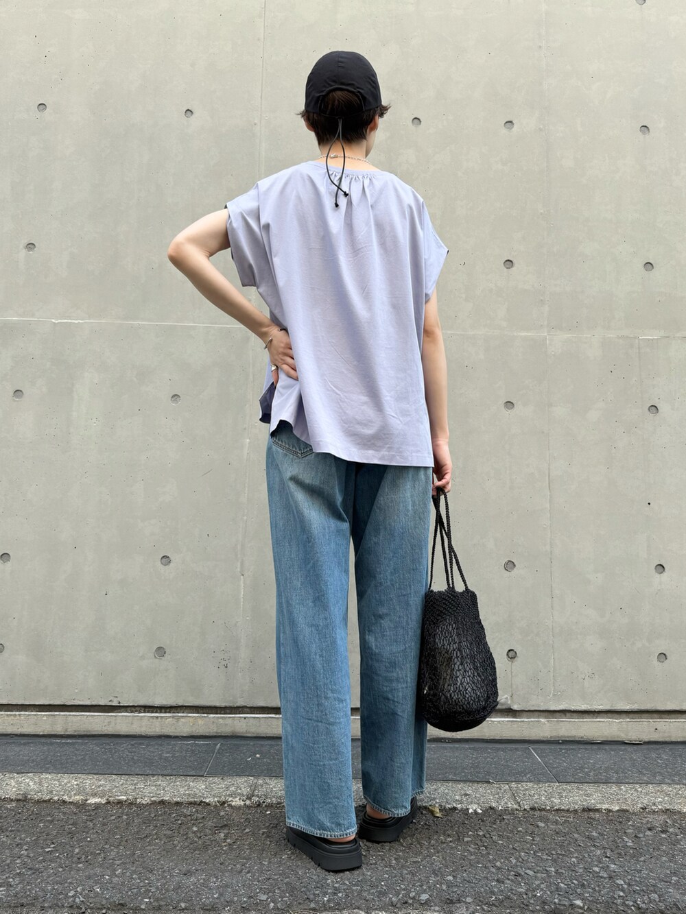 パープル系のTシャツ/カットソー、ブルー系のデニムパンツ、ブラック系のかごバッグを着用したレディースの夏コーディネートの3枚目の写真
