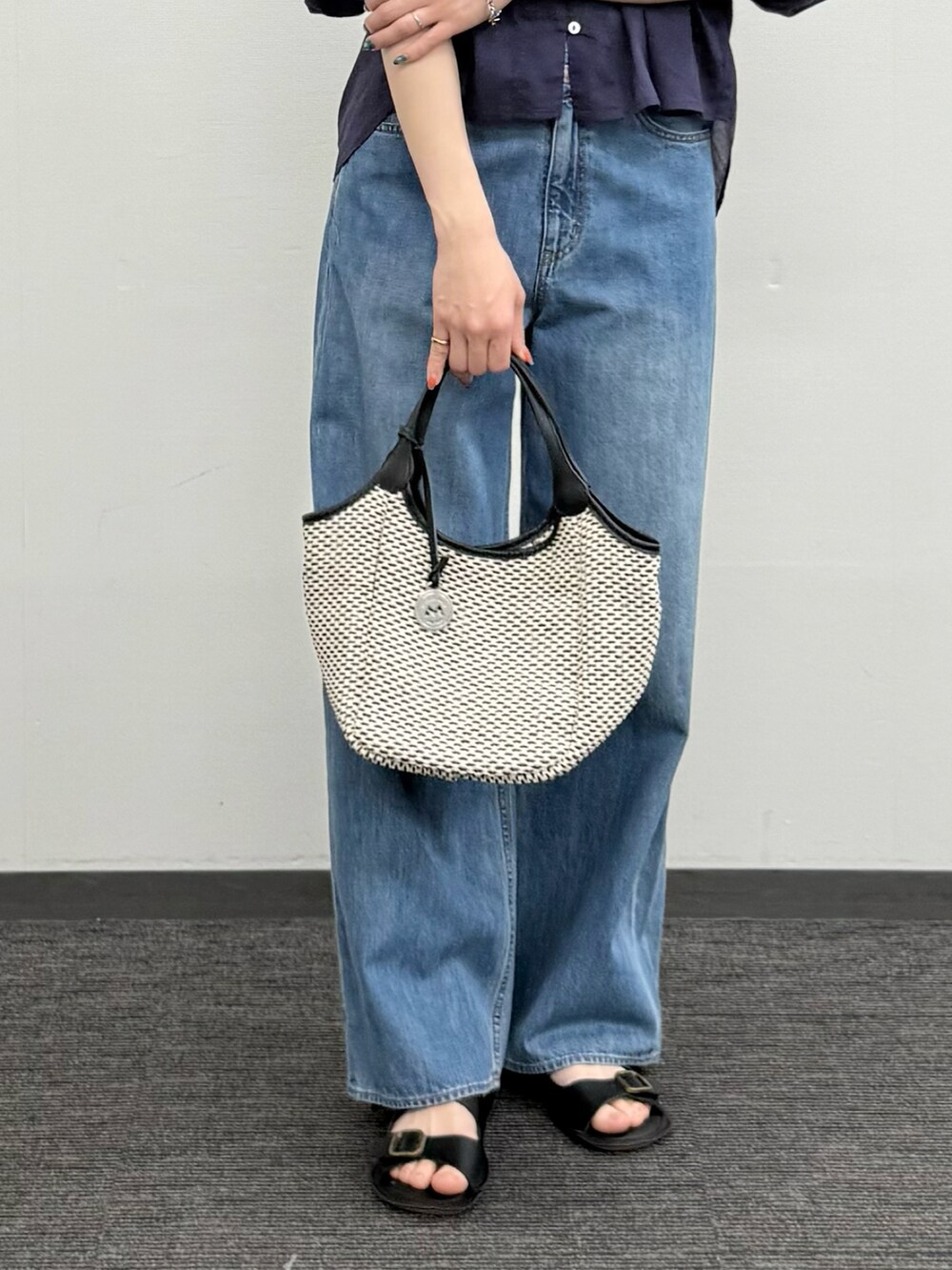 ブルー系のシャツ/ブラウス、ブルー系のデニムパンツ、ブラック系のかごバッグを着用したレディースの春コーディネートの4枚目の写真