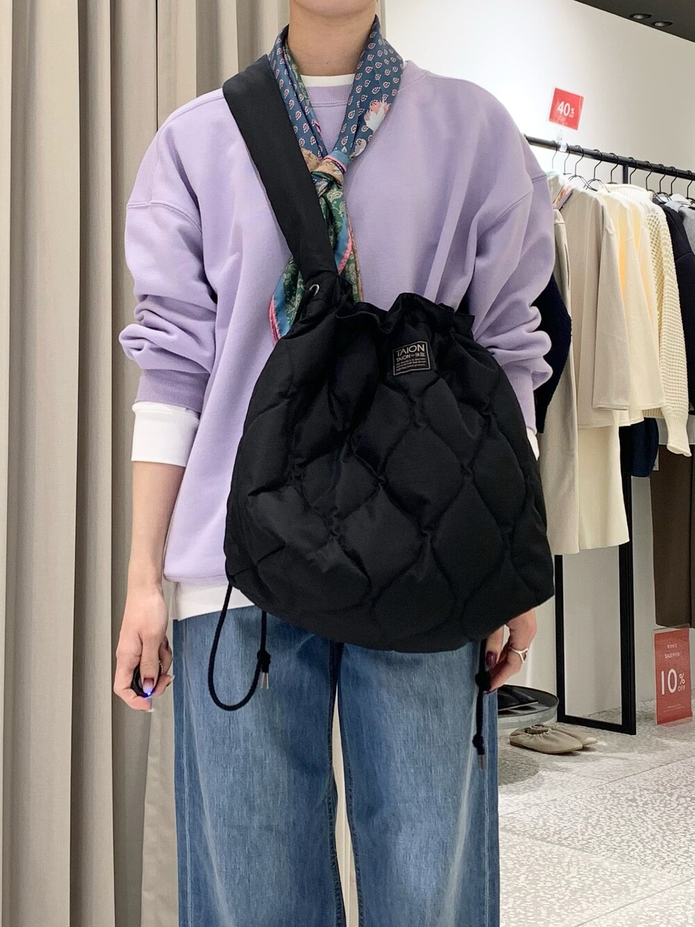 パープル系のスウェット、ブラック系のショルダーバッグ、ブルー系のデニムパンツを着用したレディースの冬コーディネートの4枚目の写真