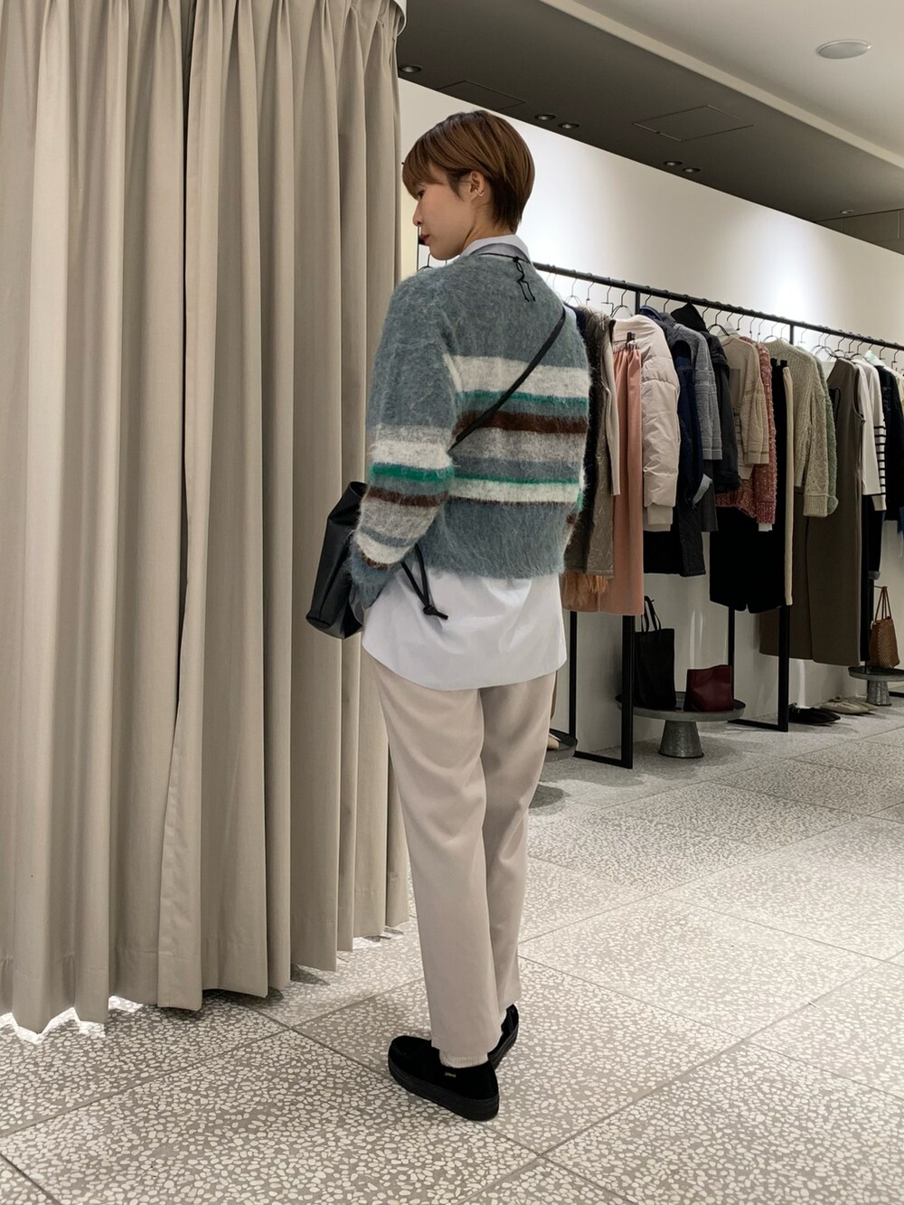 ブルー系のニット/セーター、ブラック系のショルダーバッグ、ブルー系のシャツ/ブラウスを着用したレディースの冬コーディネートの2枚目の写真